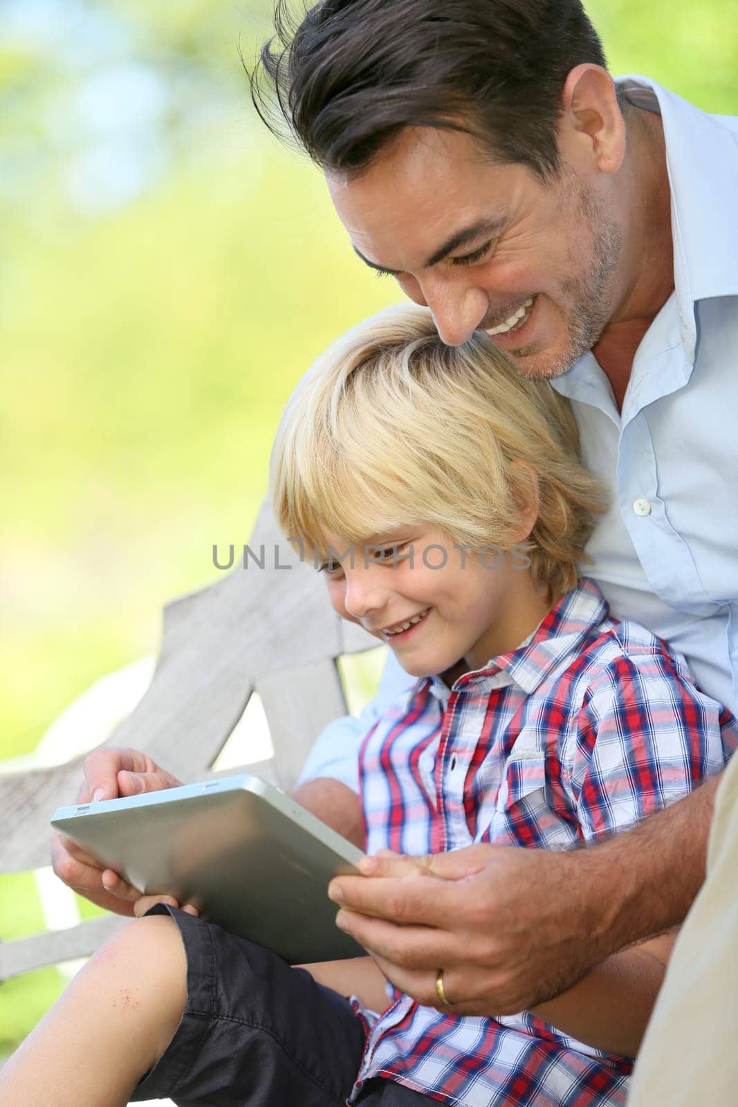 Daddy and son playing with tablet outside