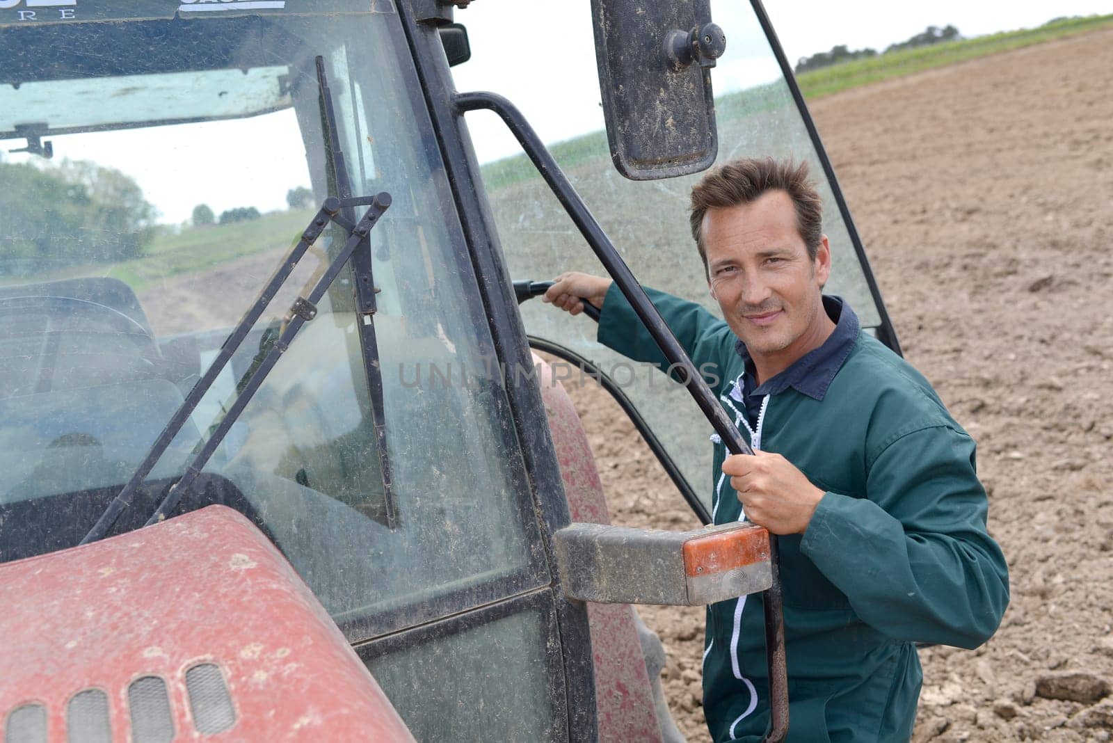Farmer climbing into tractor out in farming land