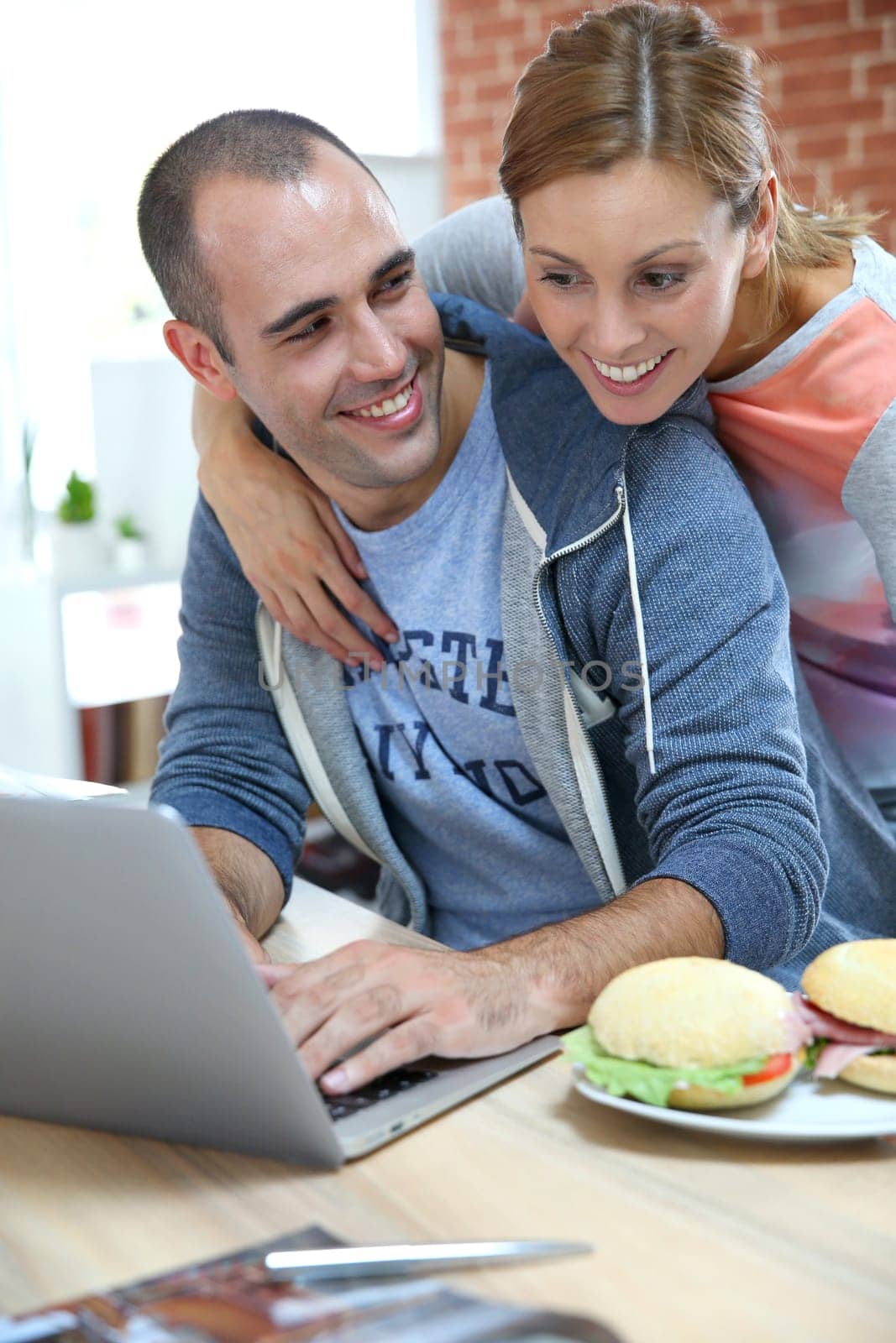 Roommates eating sandwich in front of laptop