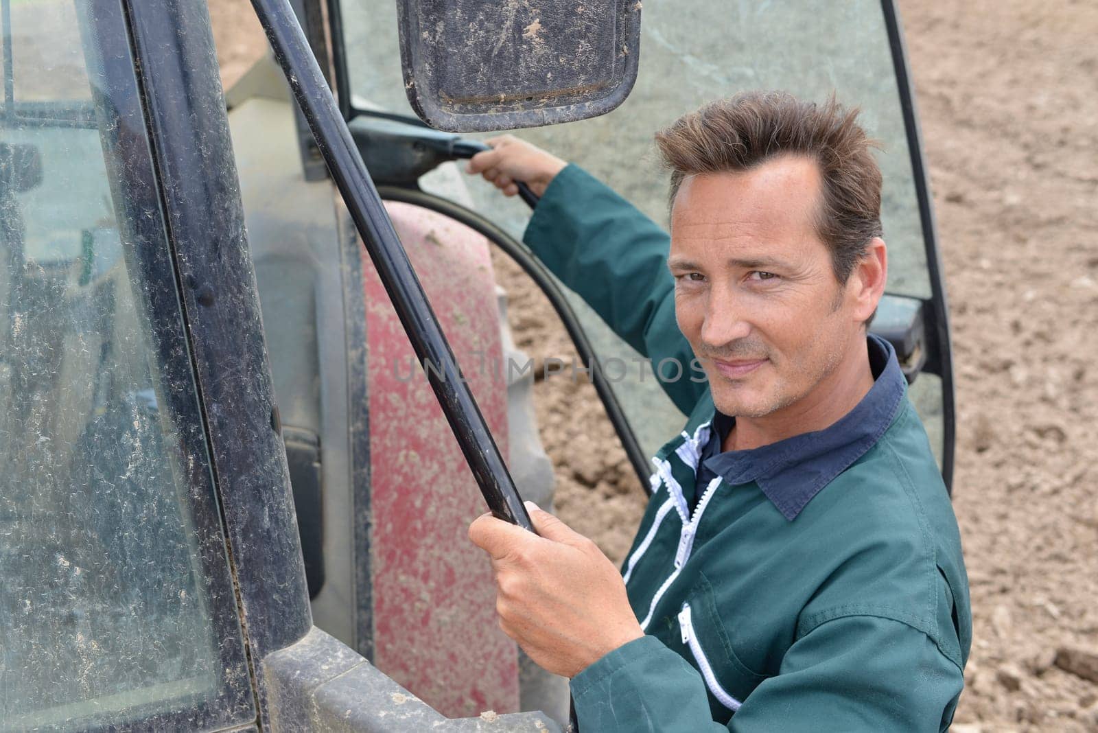 Farmer climbing into tractor out in farming land
