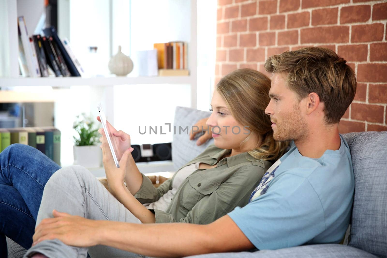 Young couple relaxing in sofa and using tablet