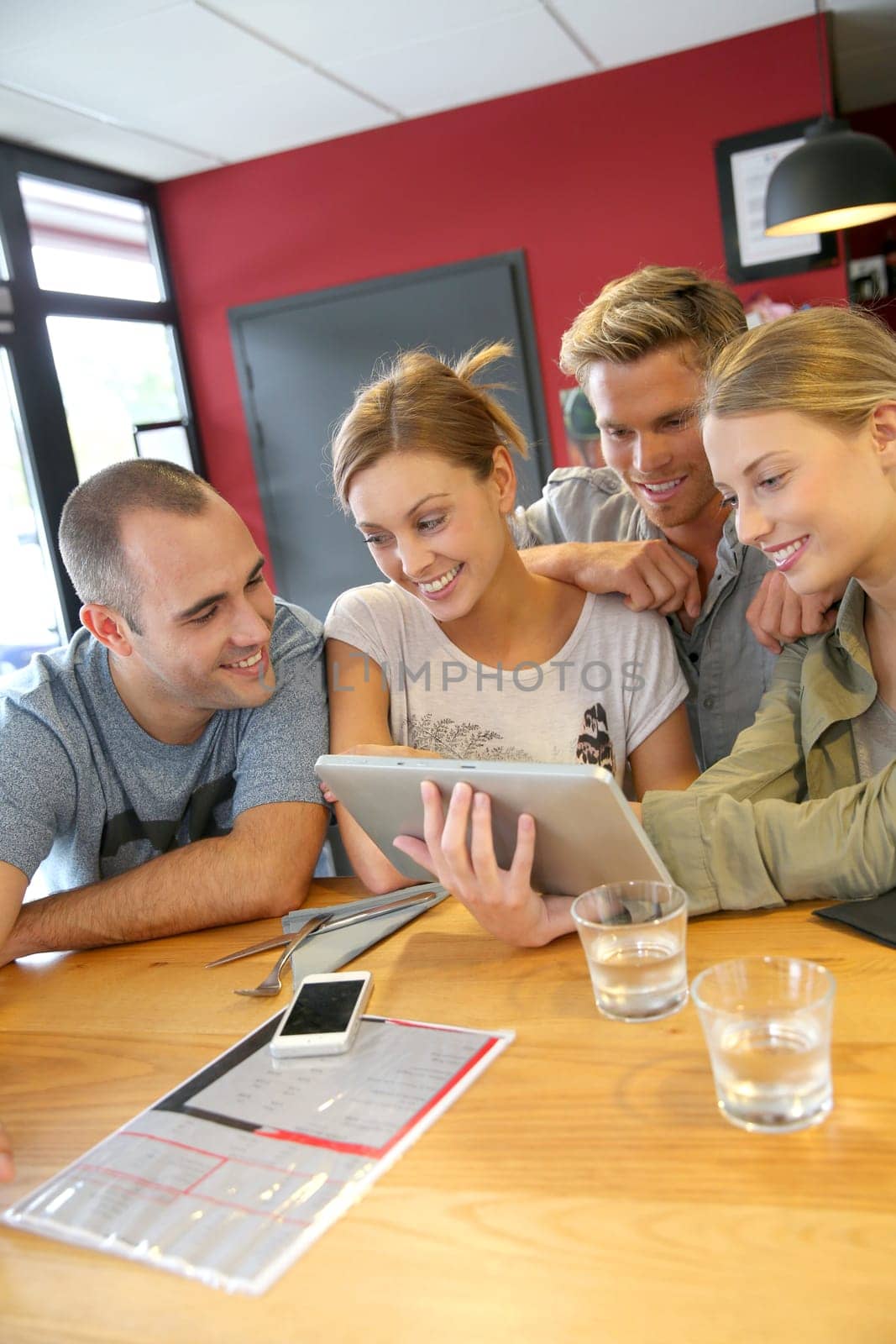 Group of friends in campus lounge websurfing with tablet
