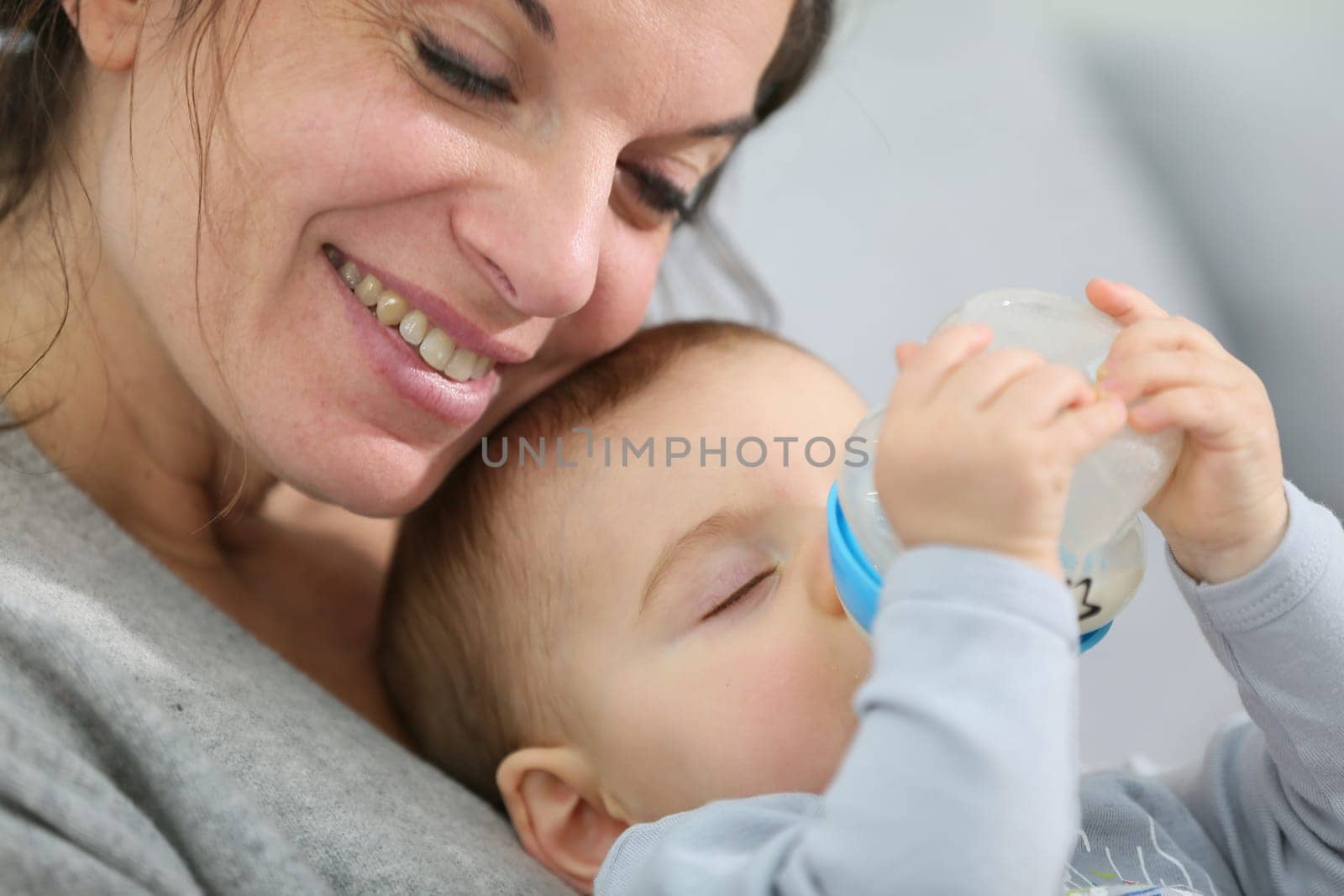 Mother and baby boy holding baby bottle