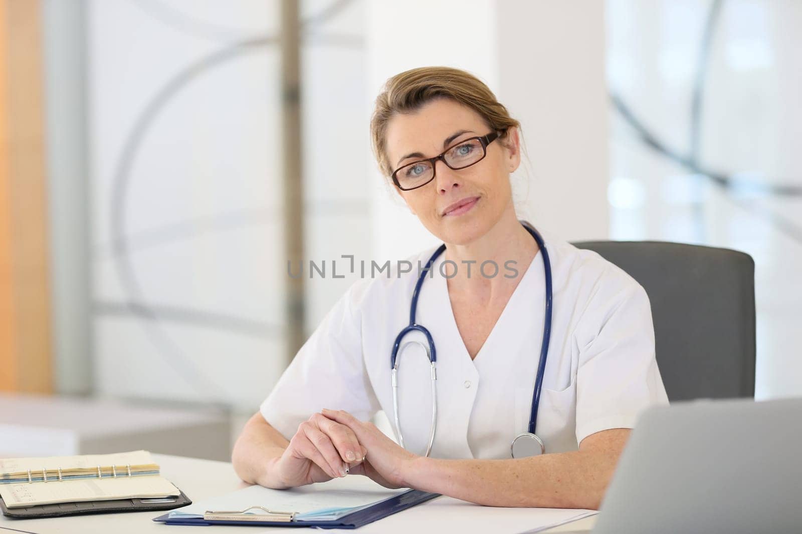 Portrait of mature nurse sitting at desk in office