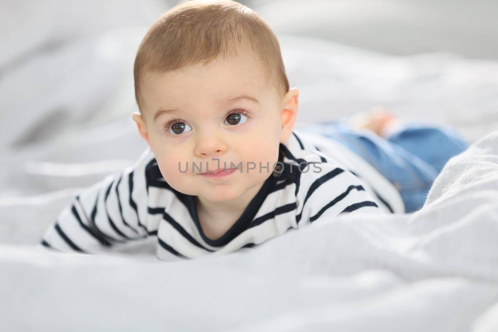 Cheerful baby boy laying over bed