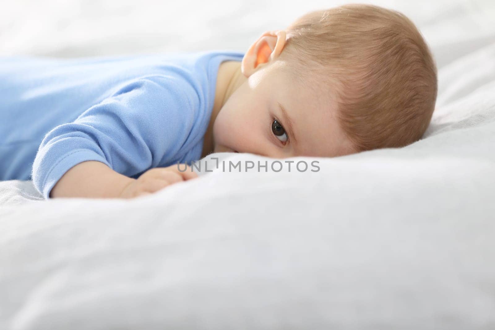 8-month-old baby boy laying on bed