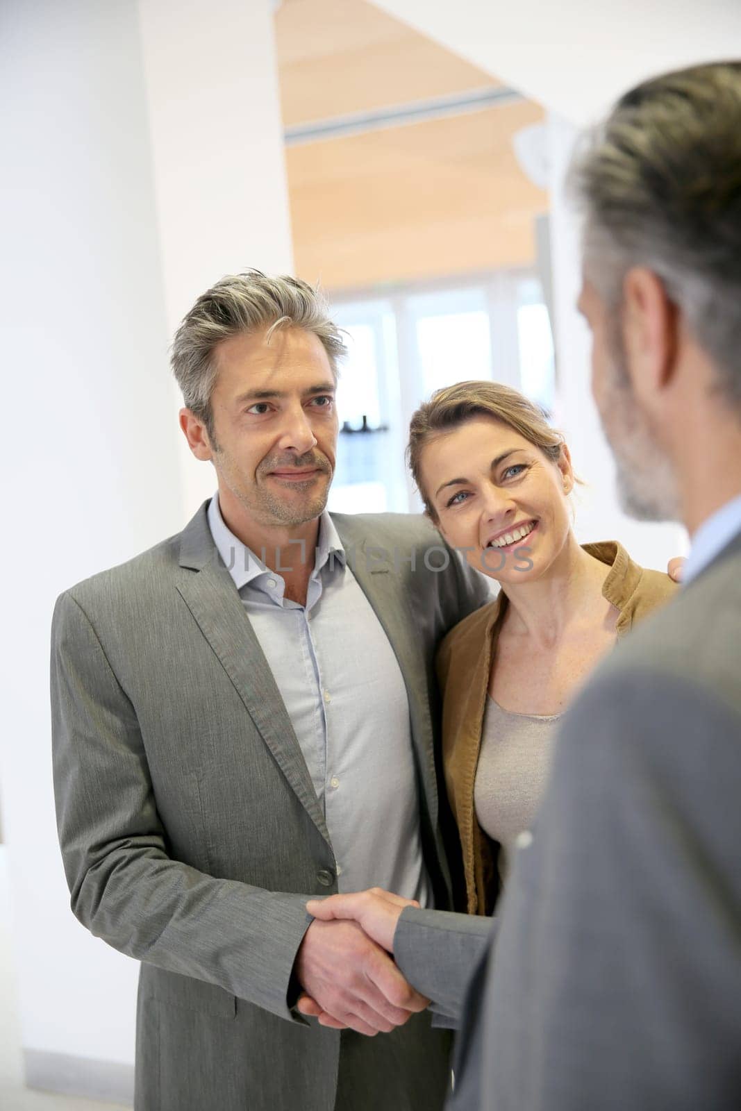 Adviser giving handshake to clients