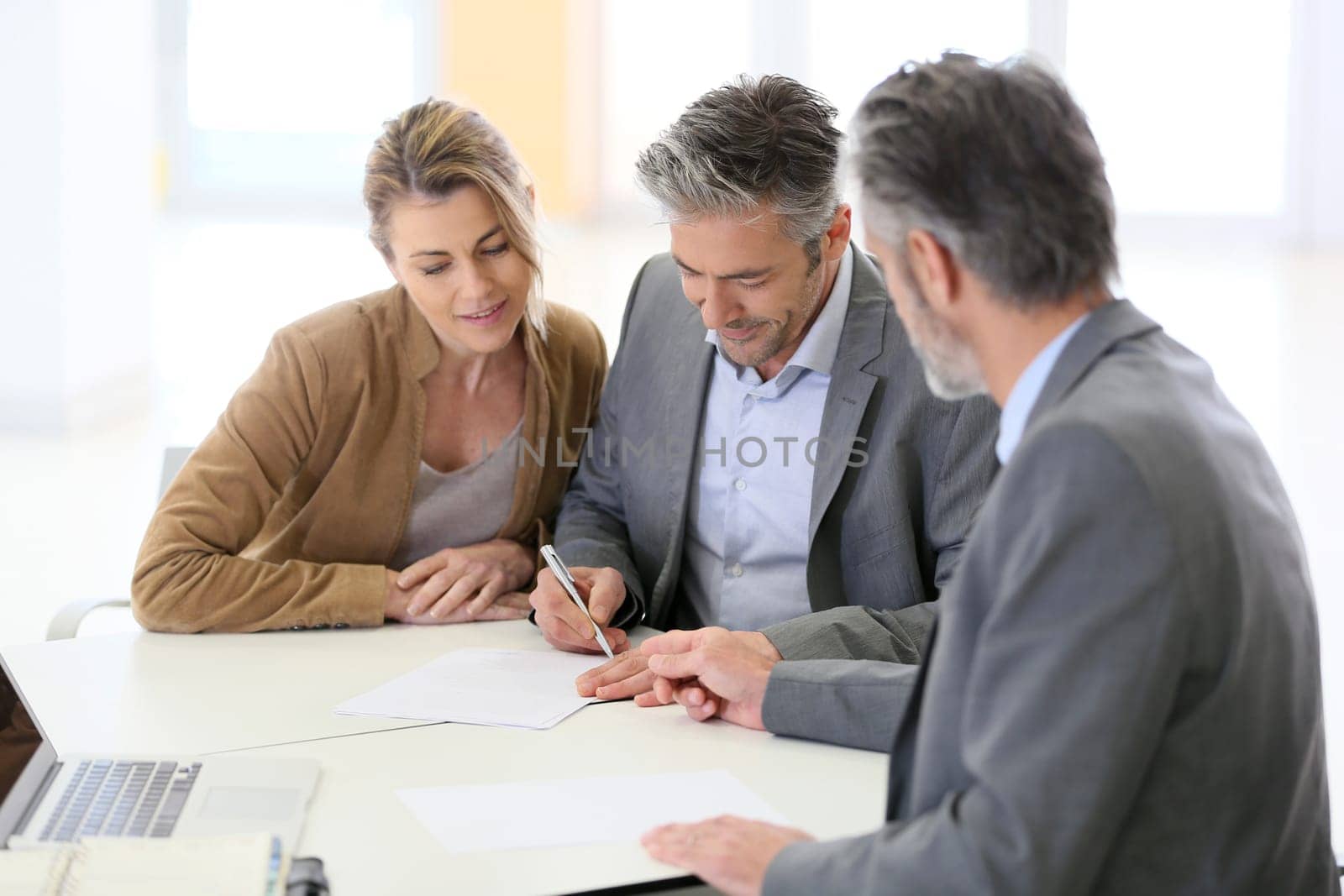 Mature couple signing financial contract at the bank