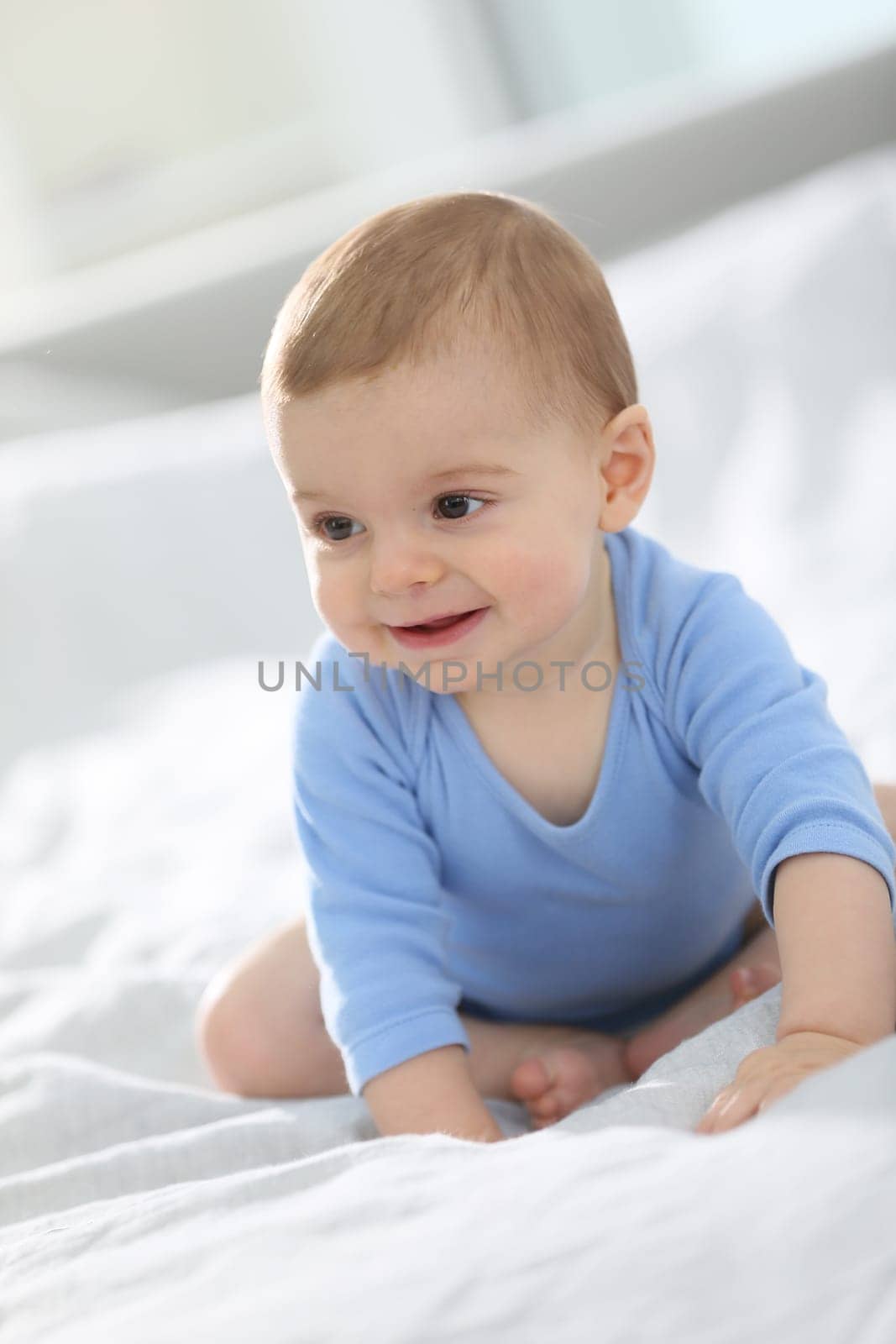 Cute baby boy sitting on bed