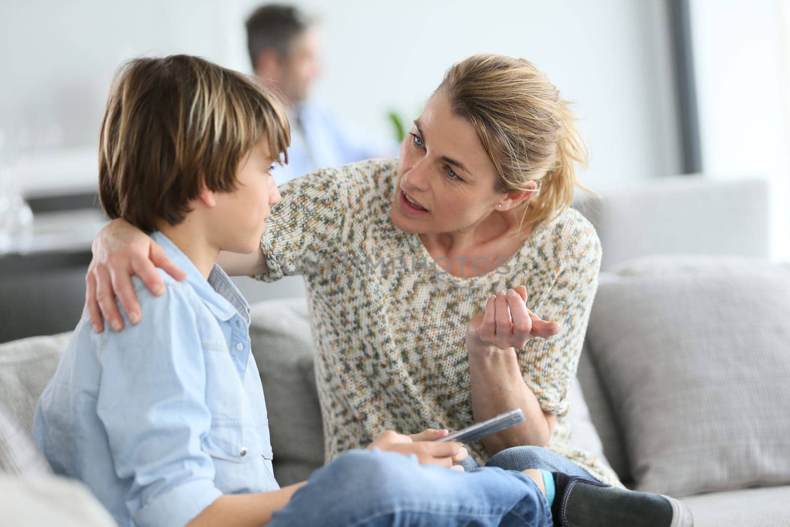Mother giving warning to young boy using smartphone