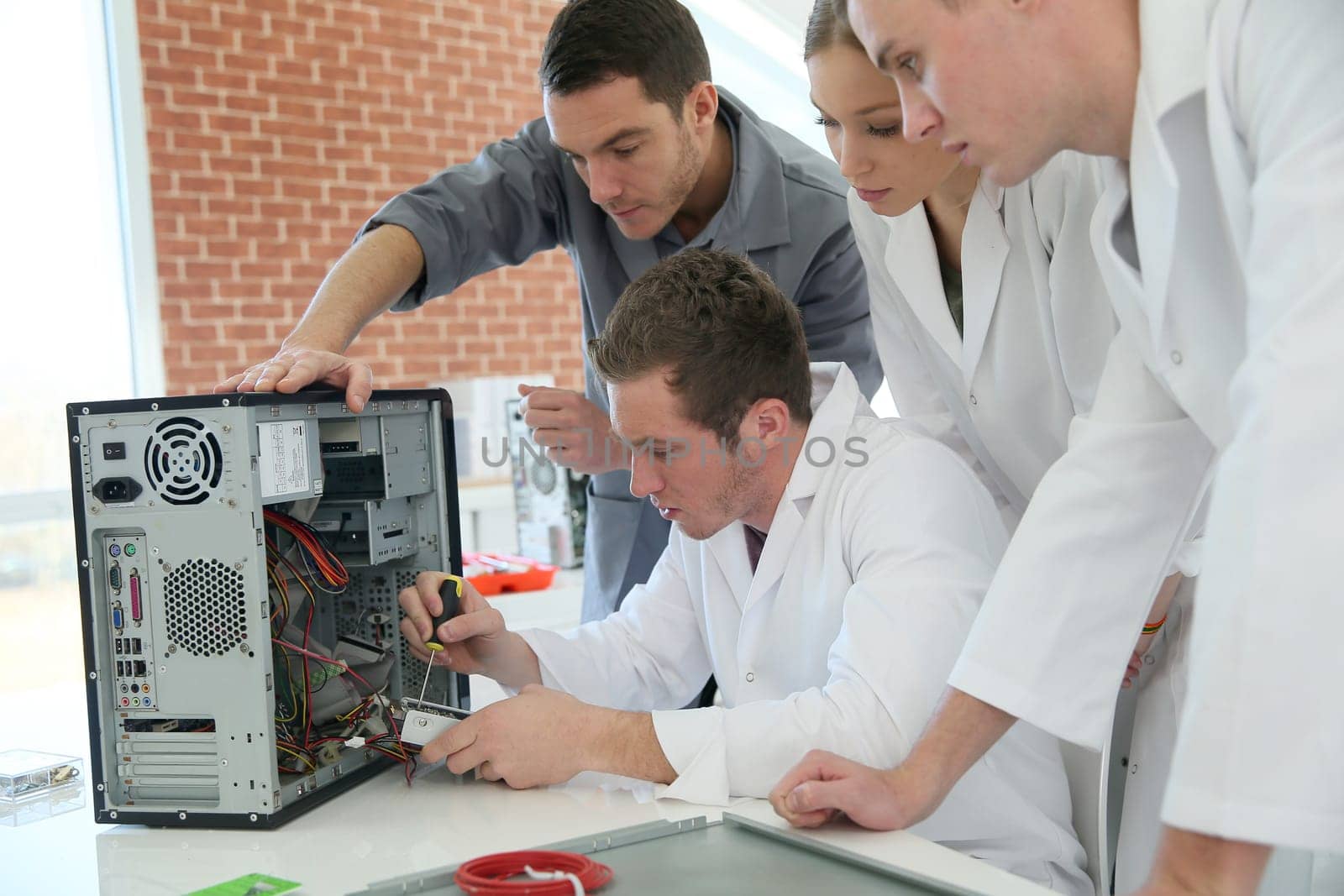 Students in computing class with teacher fixing hardware