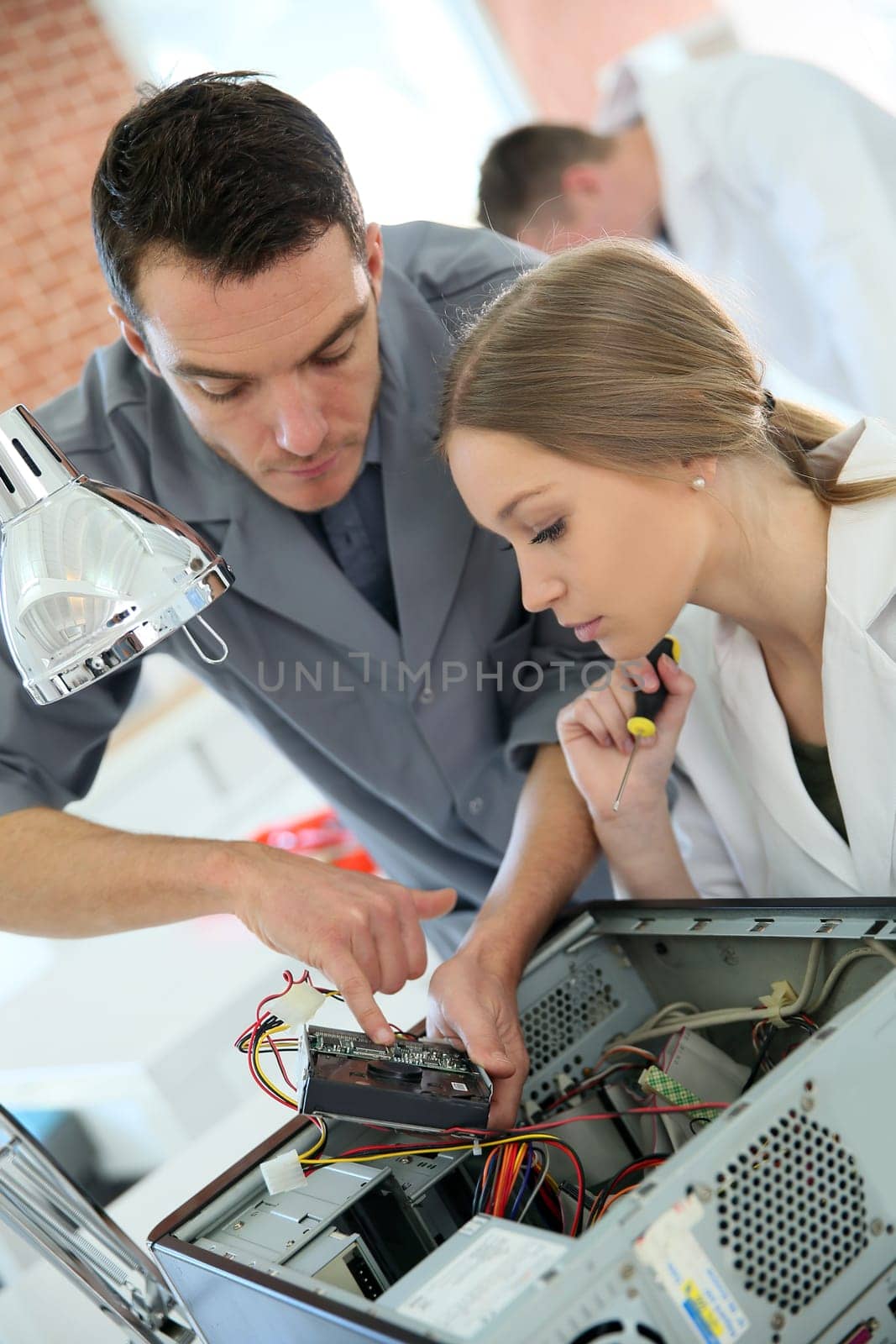 Teacher with student in technology repairing computer