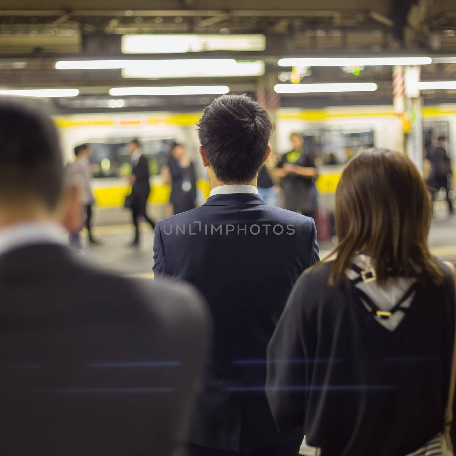 Passengers traveling by Tokyo metro. Business people commuting to work by public transport in rush hour. Shallow depth of field photo.
