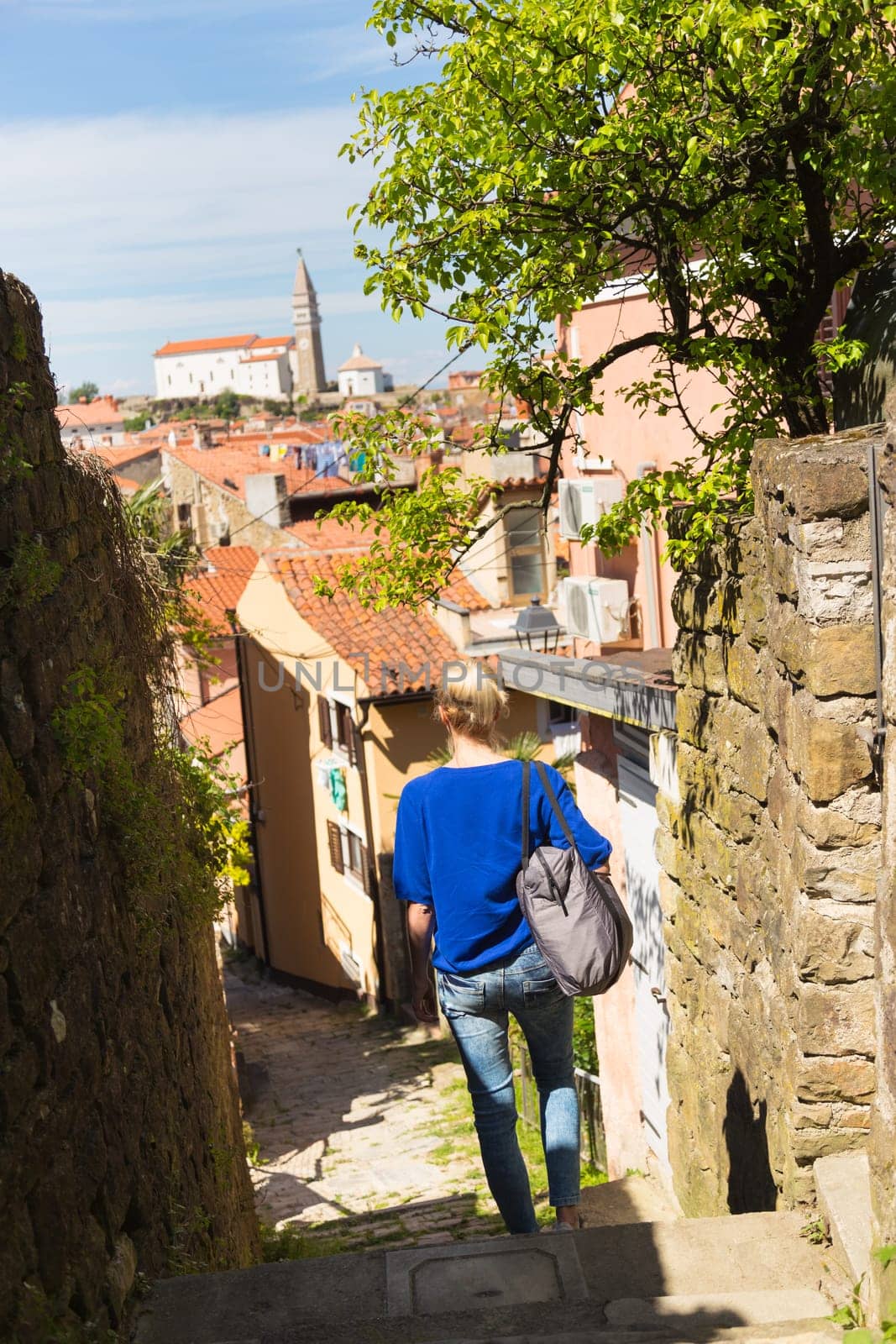 Woman walking on old traditional cobbled street in old coastal town of Piran in Slovenia, Europe.