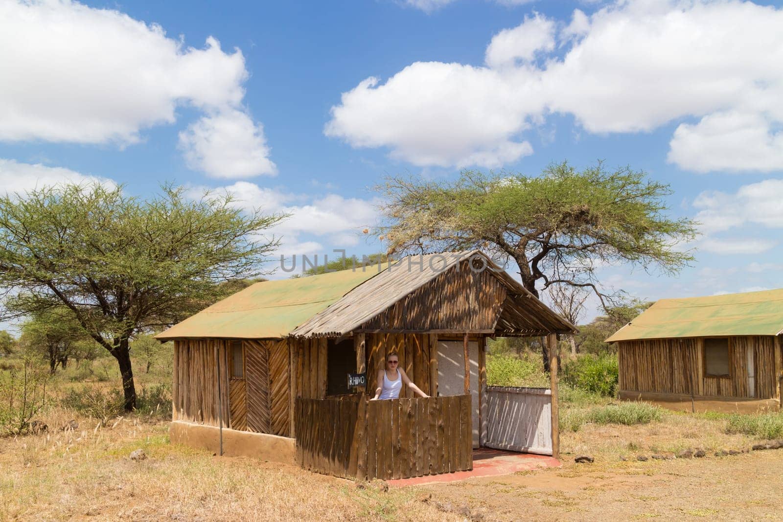 Safari vacation. Woman enjoying natural enviroment from traditional african tourist lodge.