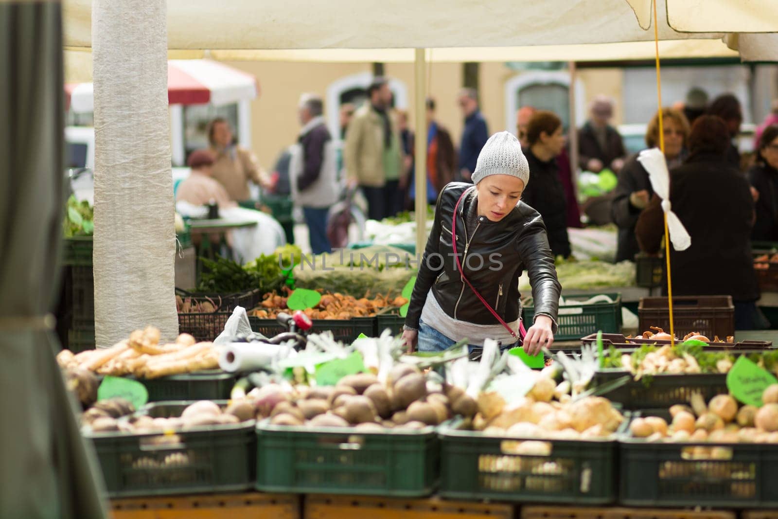 Woman buying fruits and vegetables at local food market. Market stall with variety of organic vegetable.