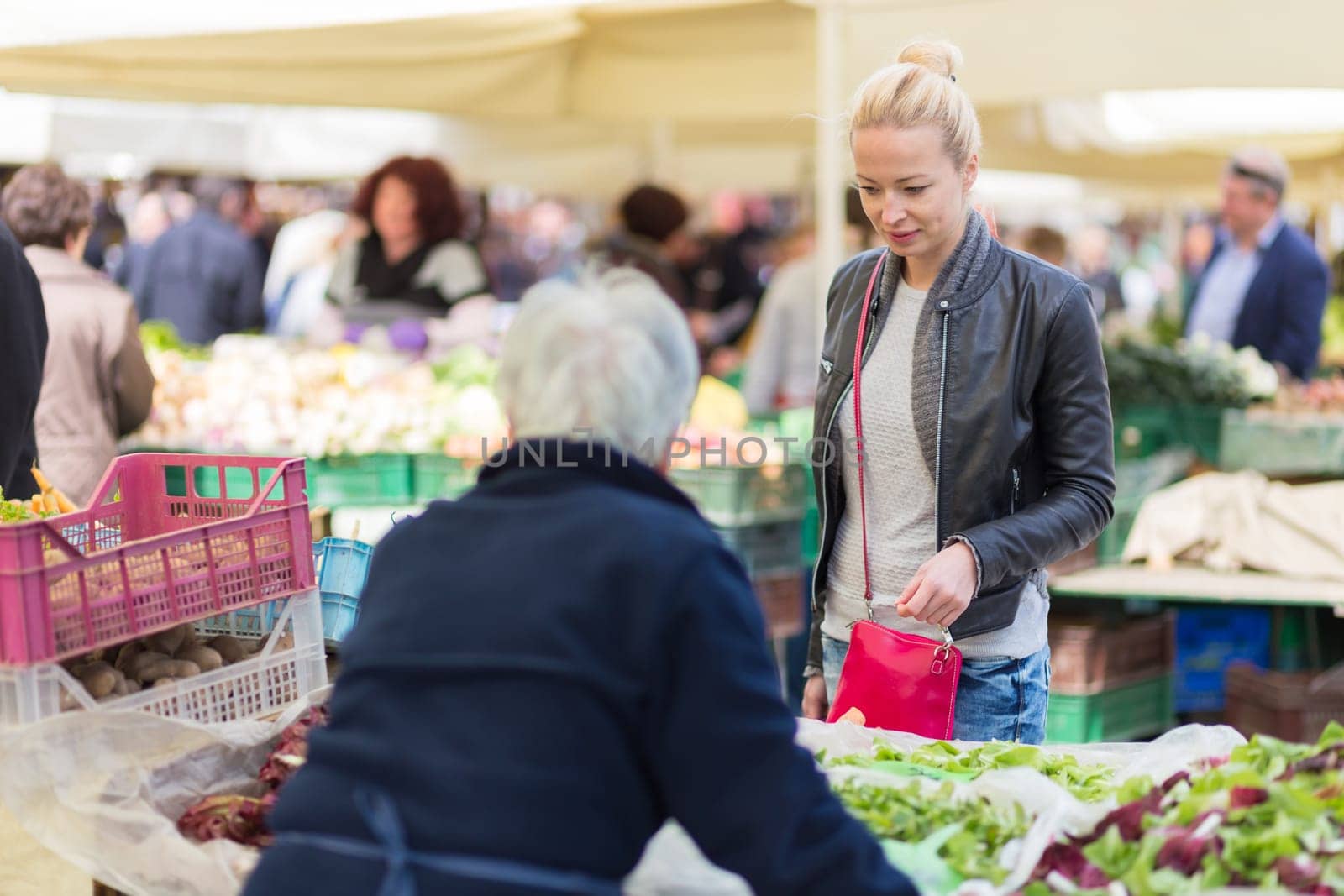 Woman buying fruits and vegetables at local food market. Market stall with variety of organic vegetable.