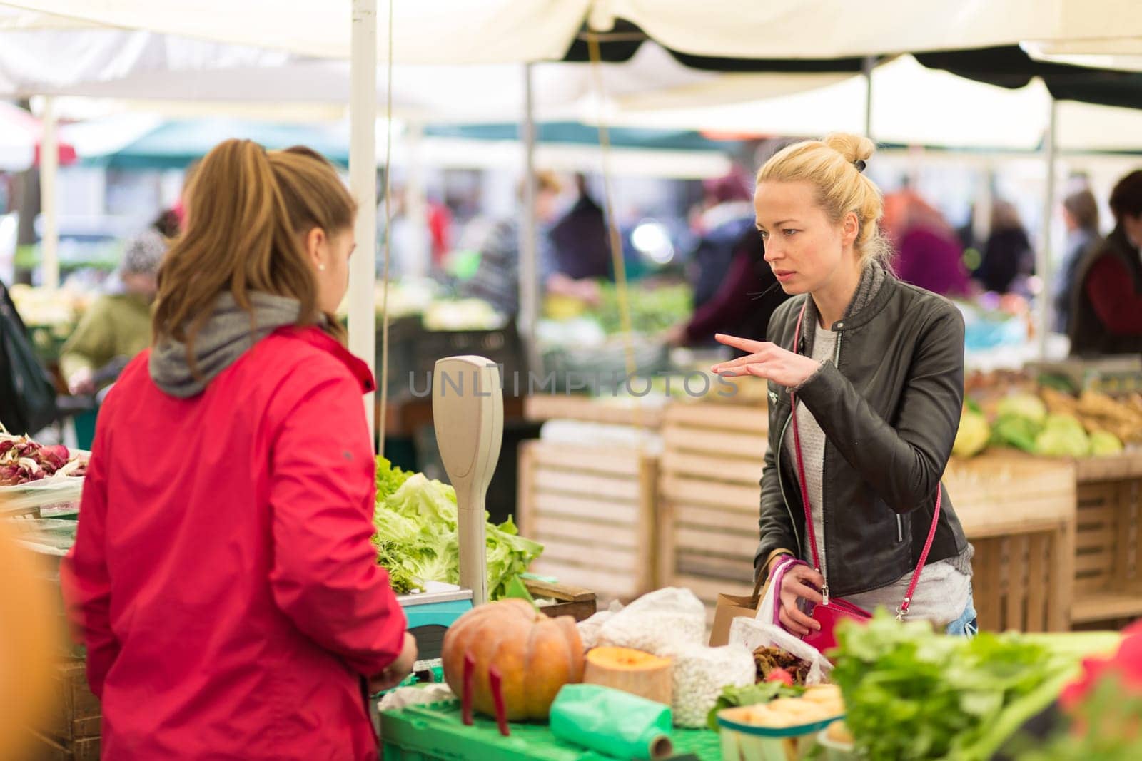 Woman buying fruits and vegetables at local food market. Market stall with variety of organic vegetable.