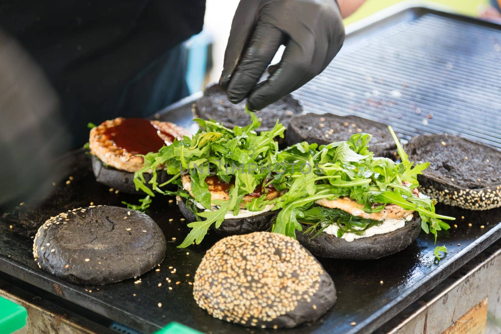 Chef making beef burgers outdoor on open kitchen international food festival event. Street food ready to serve on a food stall.