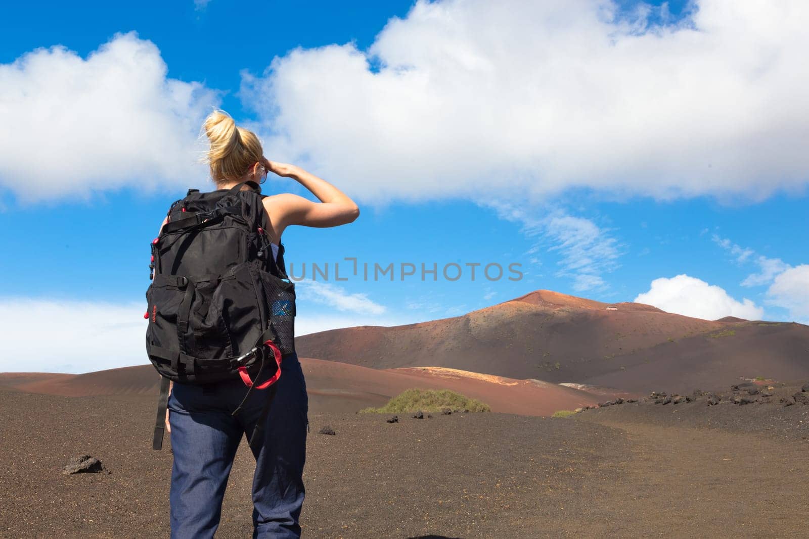 Woman hiking in nature can see the peak of Timanfaya volcano, nearly made it to top.