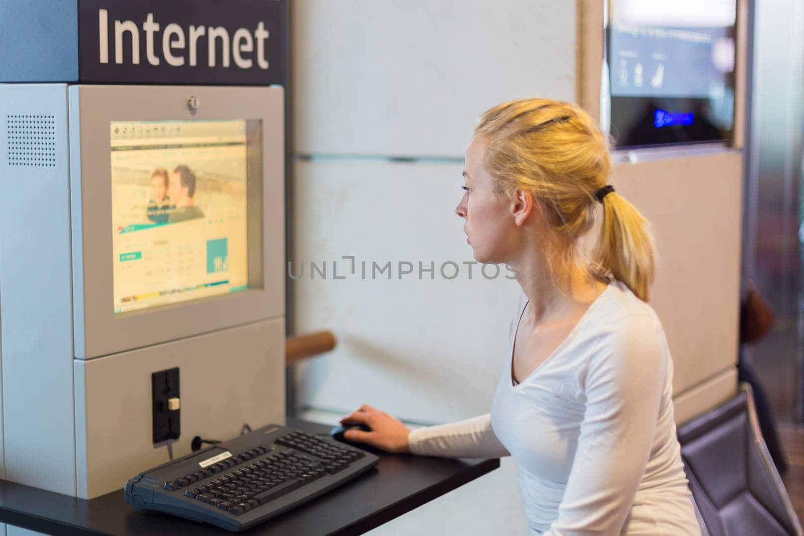 Young caucasian woman using comupter with public internet access point on airport.
