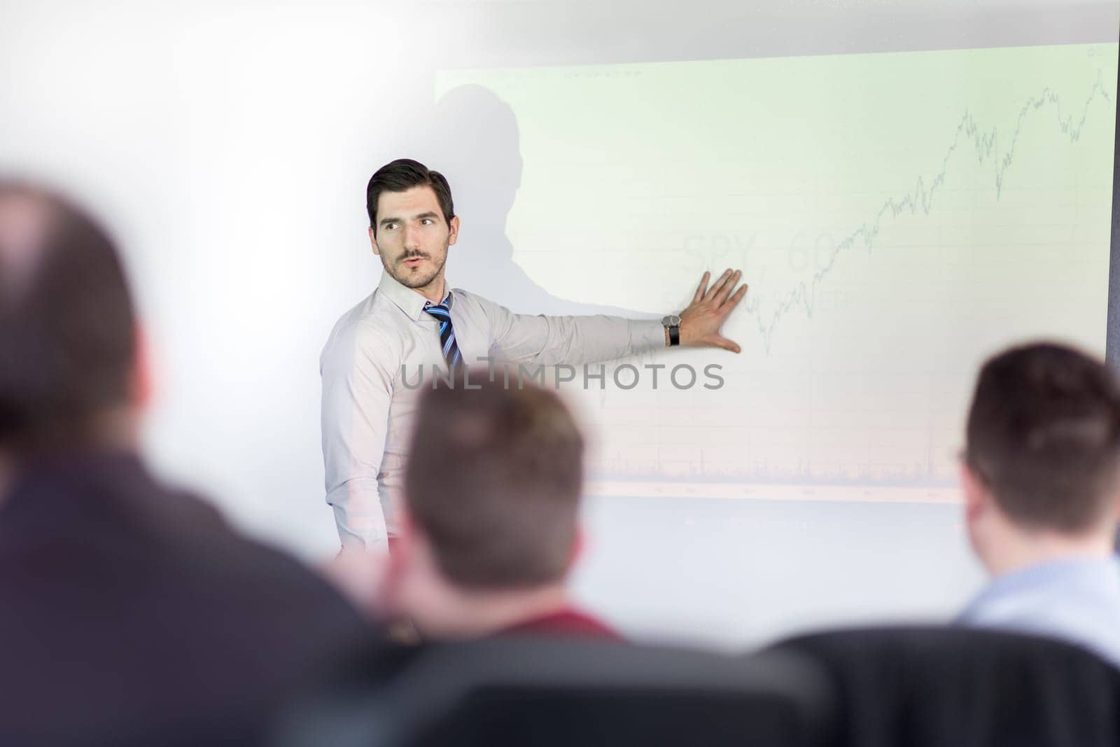 Business man making a presentation at office. Business executive delivering a presentation to his colleagues during meeting or in-house business training, explaining business plans to his employees.