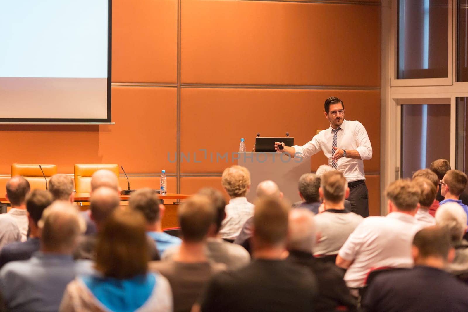 Speaker giving a talk in conference hall at business event. Audience at the conference hall. Business and Entrepreneurship.