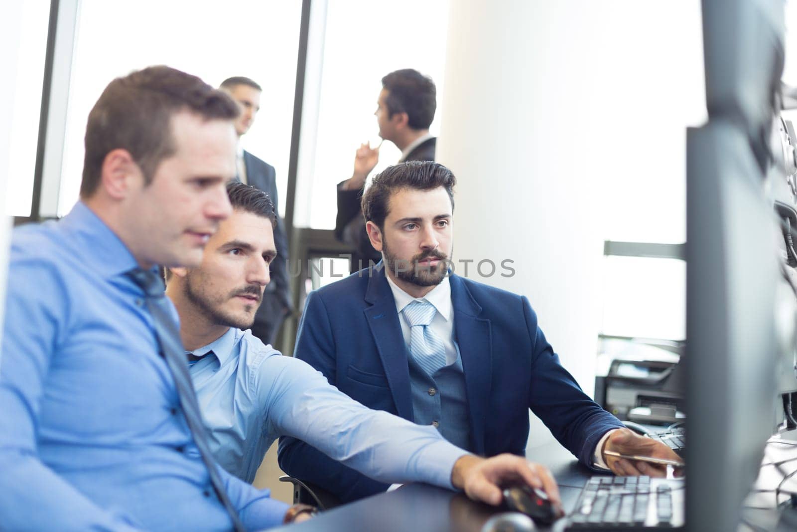Business team looking at data on multiple computer screens in corporate office. Business people trading online. Business, entrepreneurship and team work concept.
