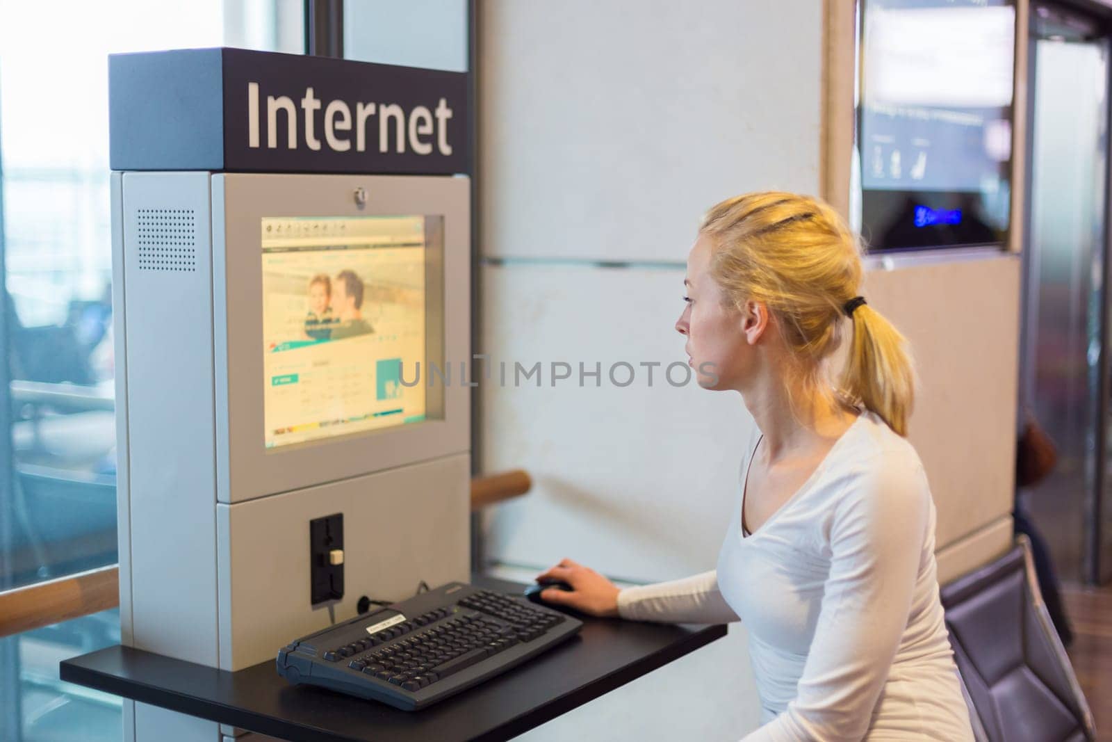 Young caucasian woman using comupter with public internet access point on airport.