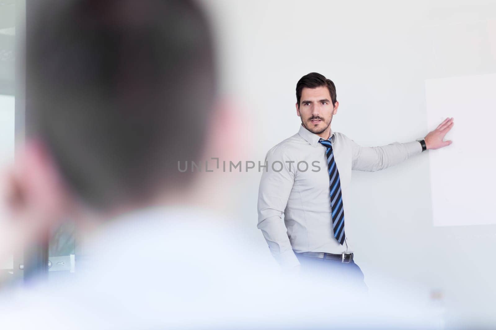 Business man making a presentation at office. Business executive delivering a presentation to his colleagues during meeting or in-house business training, explaining business plans to his employees.