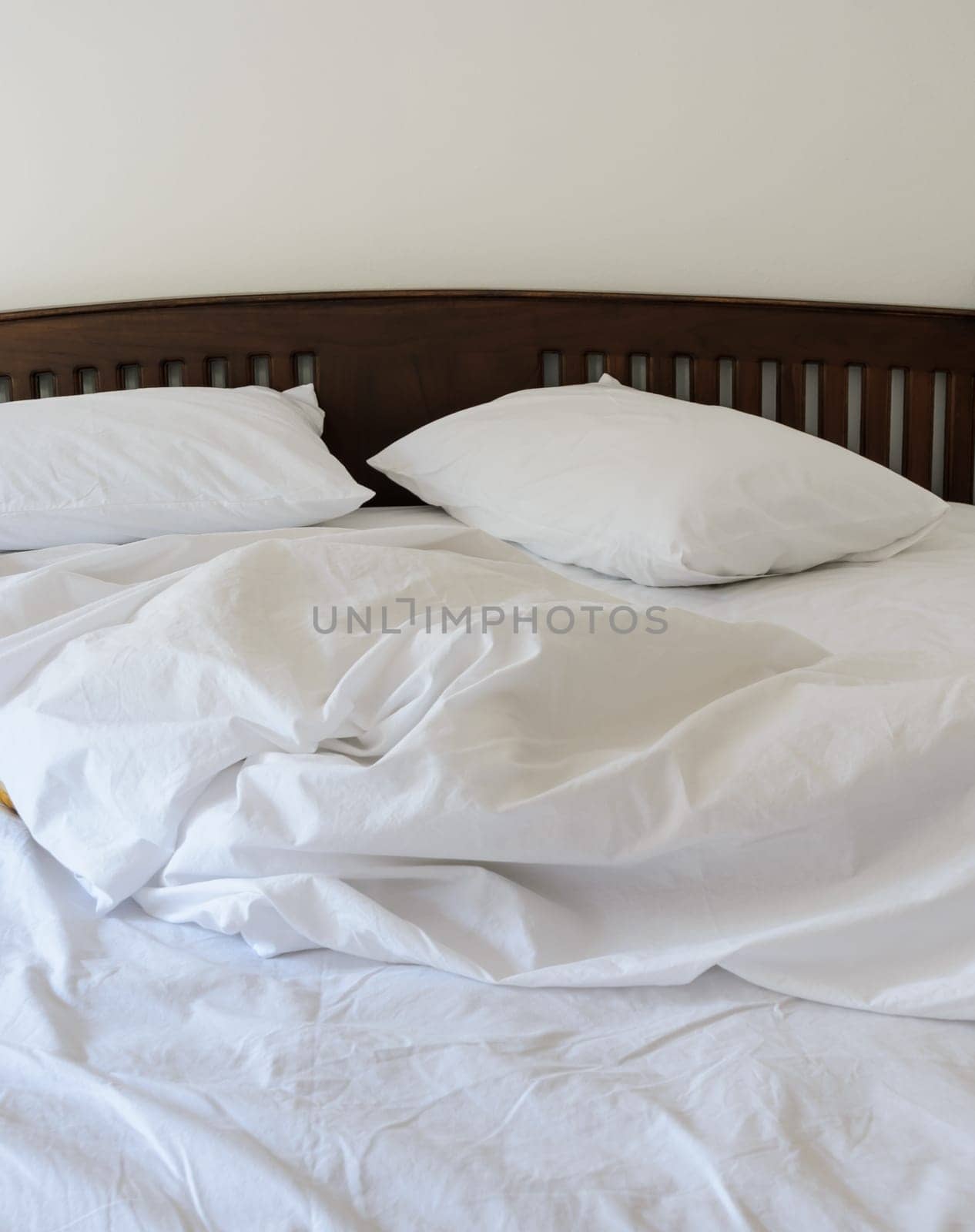 Morning view of an unmade bed in white bedroom