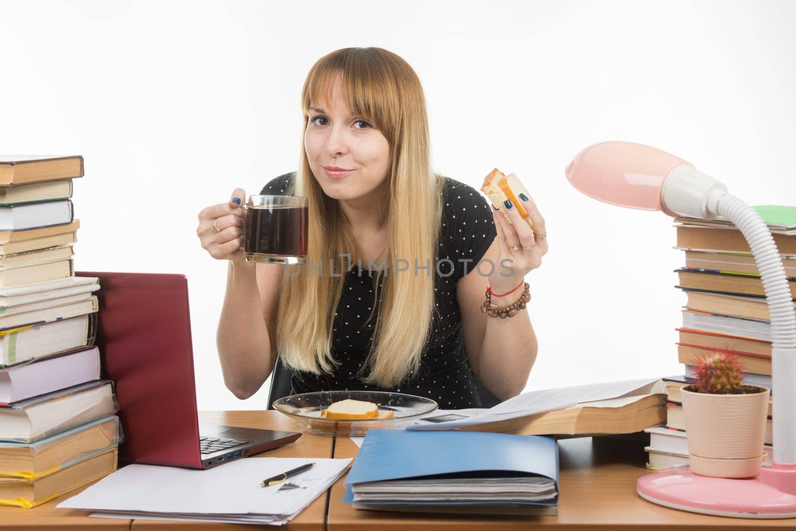 Young teacher drinks coffee with a sandwich in the workplace