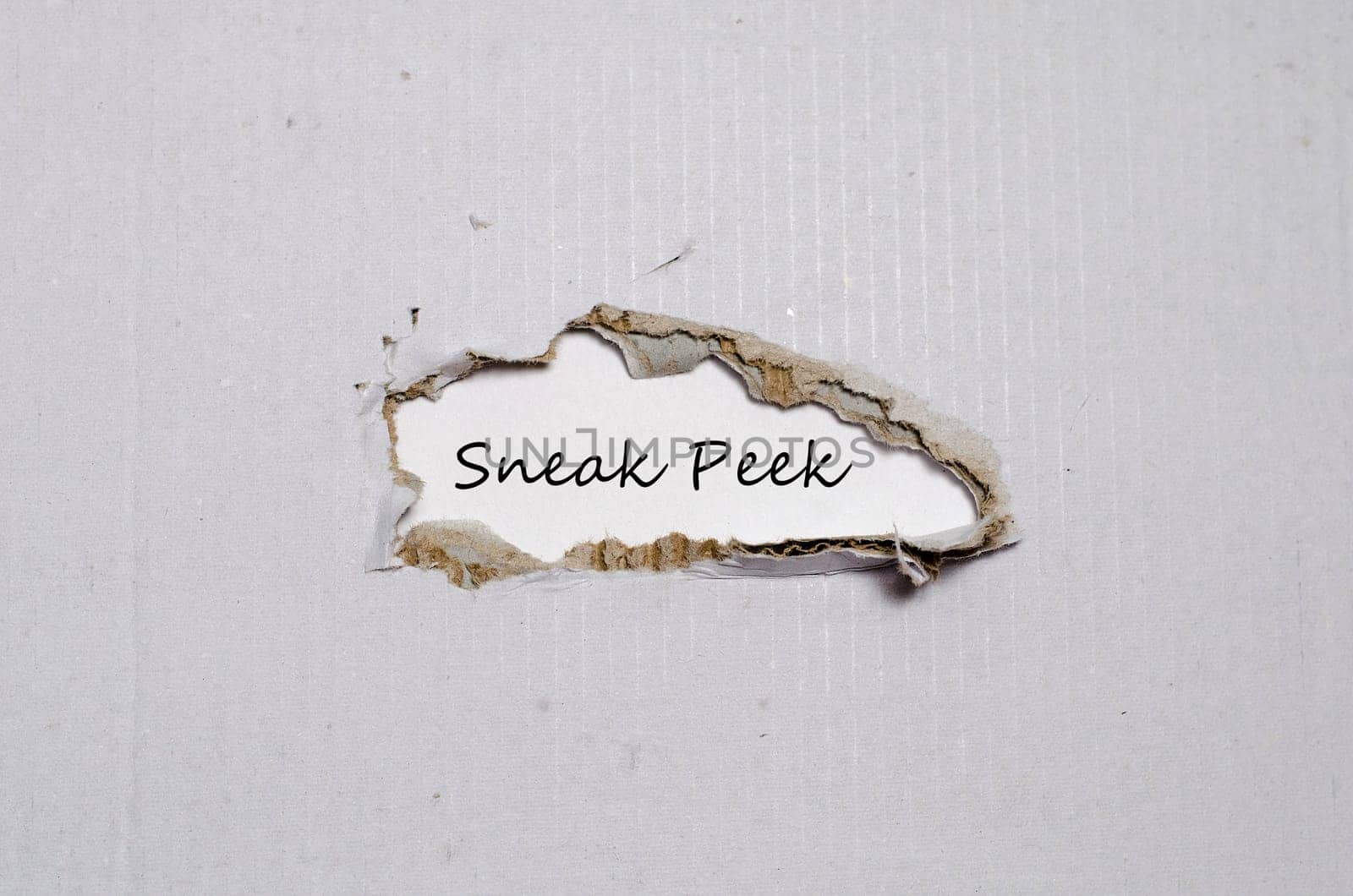 The word sneak peek appearing behind torn paper.