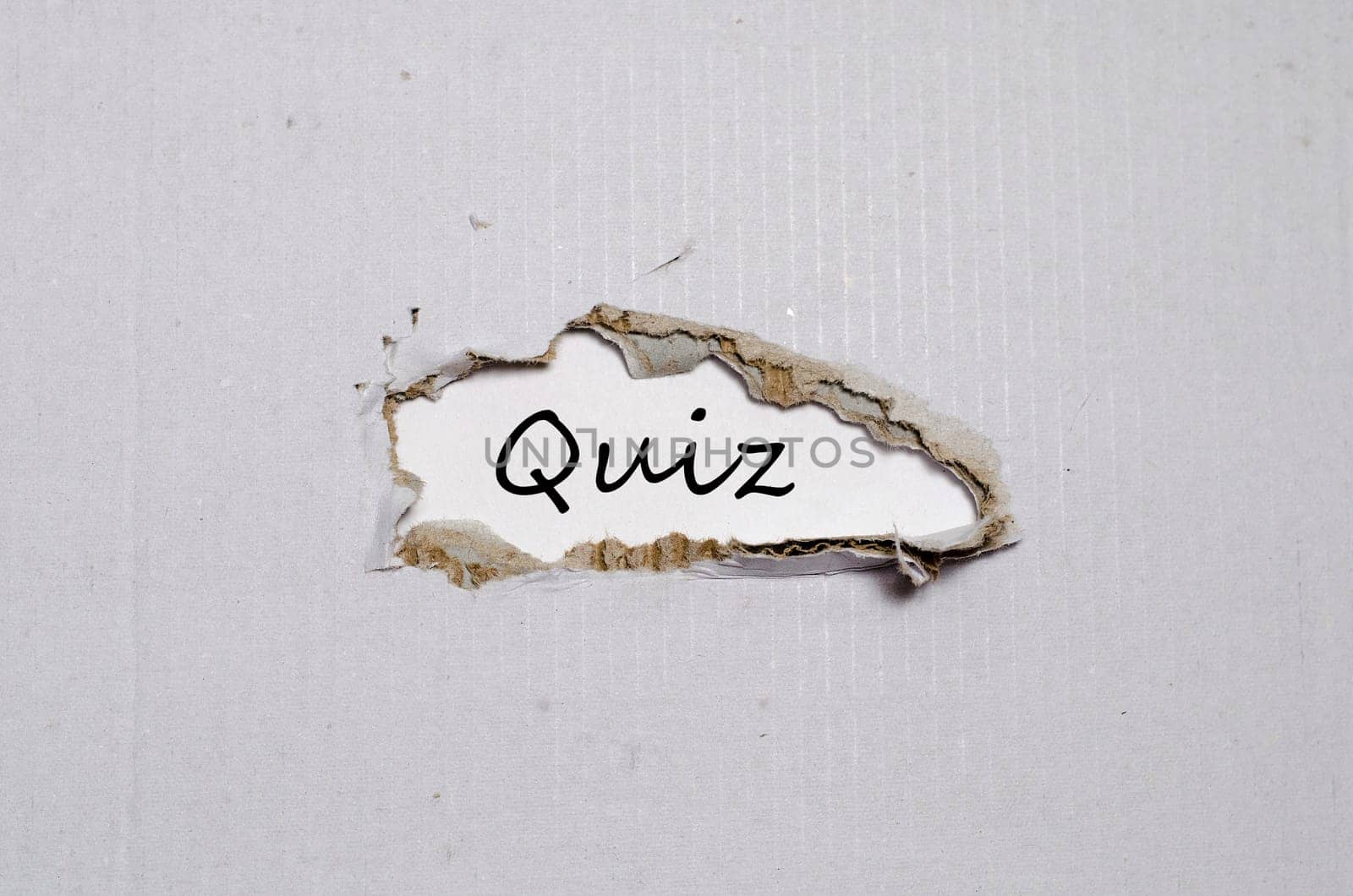The word quiz appearing behind torn paper.