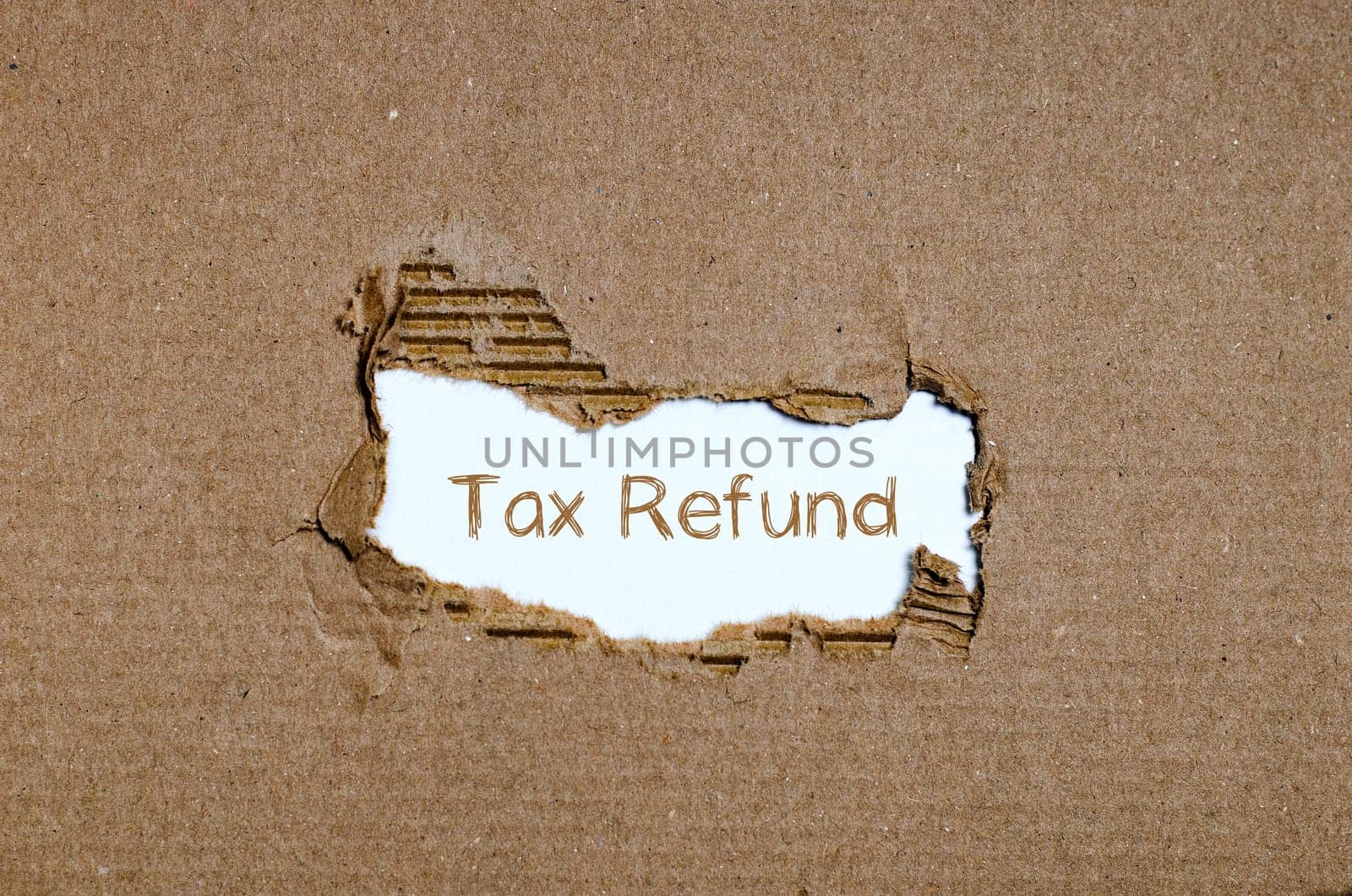 The word tax refund appearing behind torn paper.