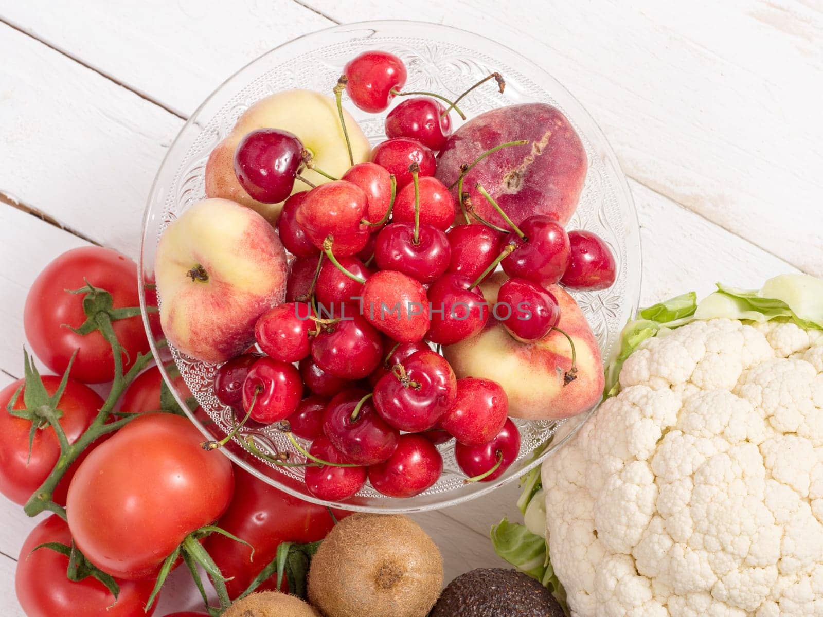 cherries and peaches cup with some vegetables on white table