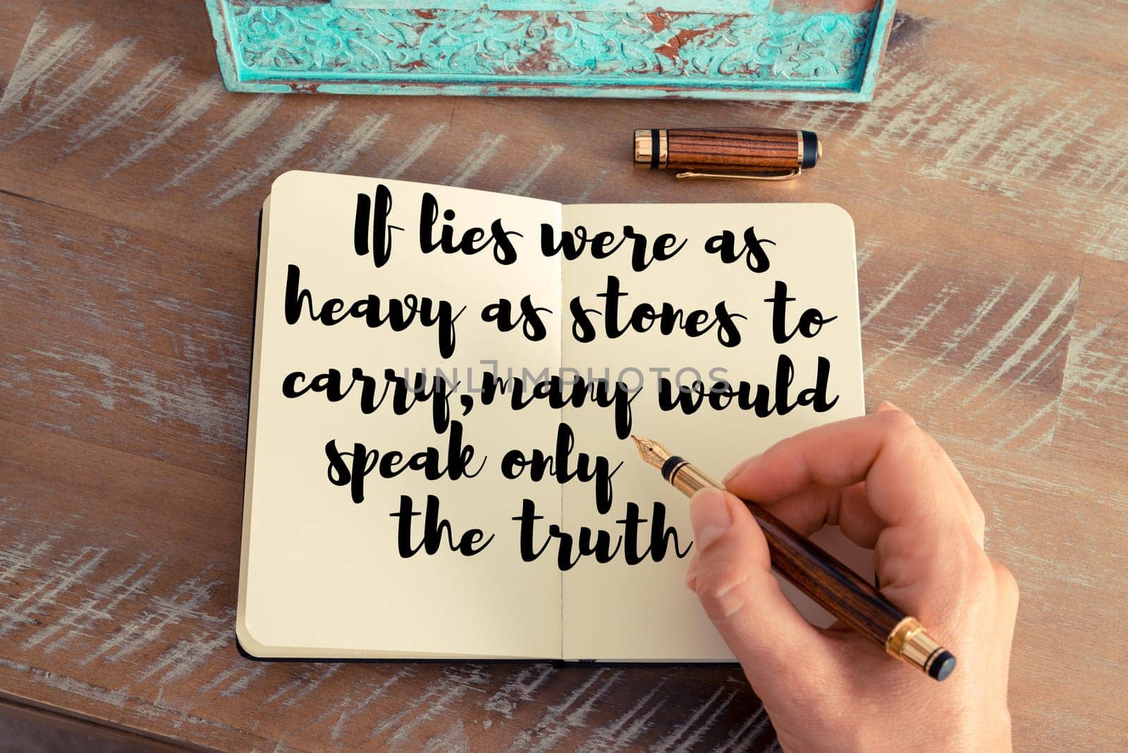 Retro effect and toned image of a woman hand writing on a notebook. Handwritten quote If lies were as heavy as stones to carry, many would speak only the truth as inspirational concept image