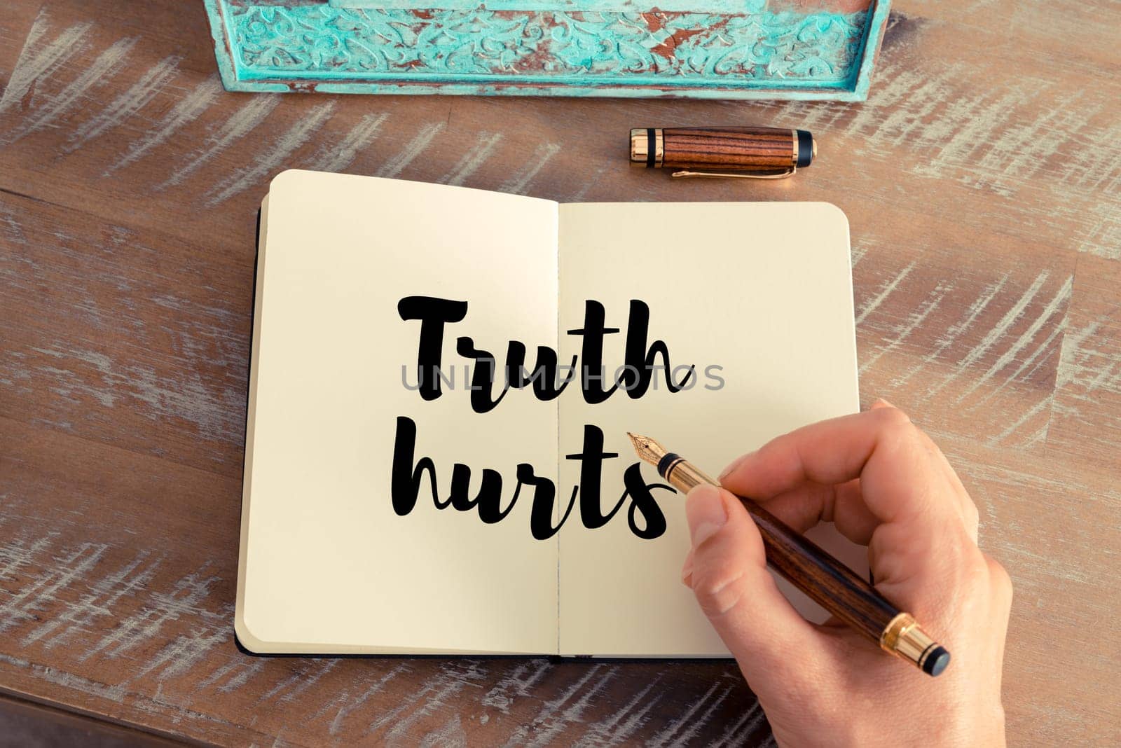 Retro effect and toned image of a woman hand writing on a notebook. Handwritten quote Truth hurts as inspirational concept image
