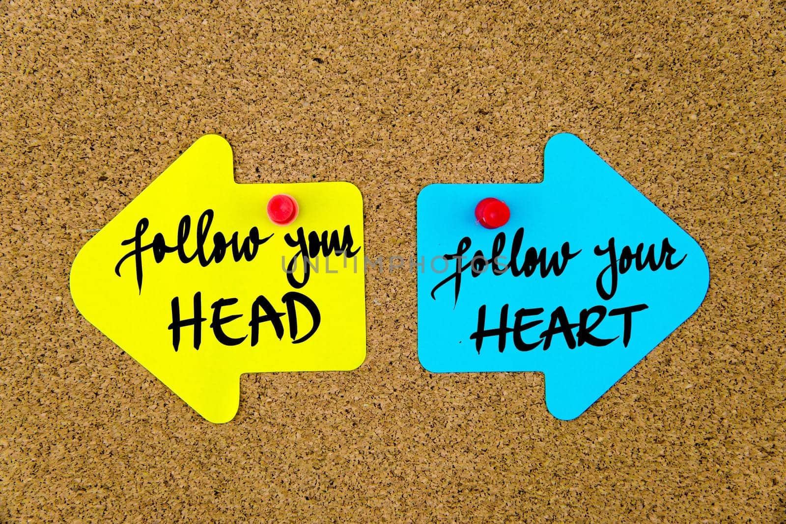 Blank yellow and blue paper notes in shape of opposite arrows pinned on cork board with thumbtacks, copy space available