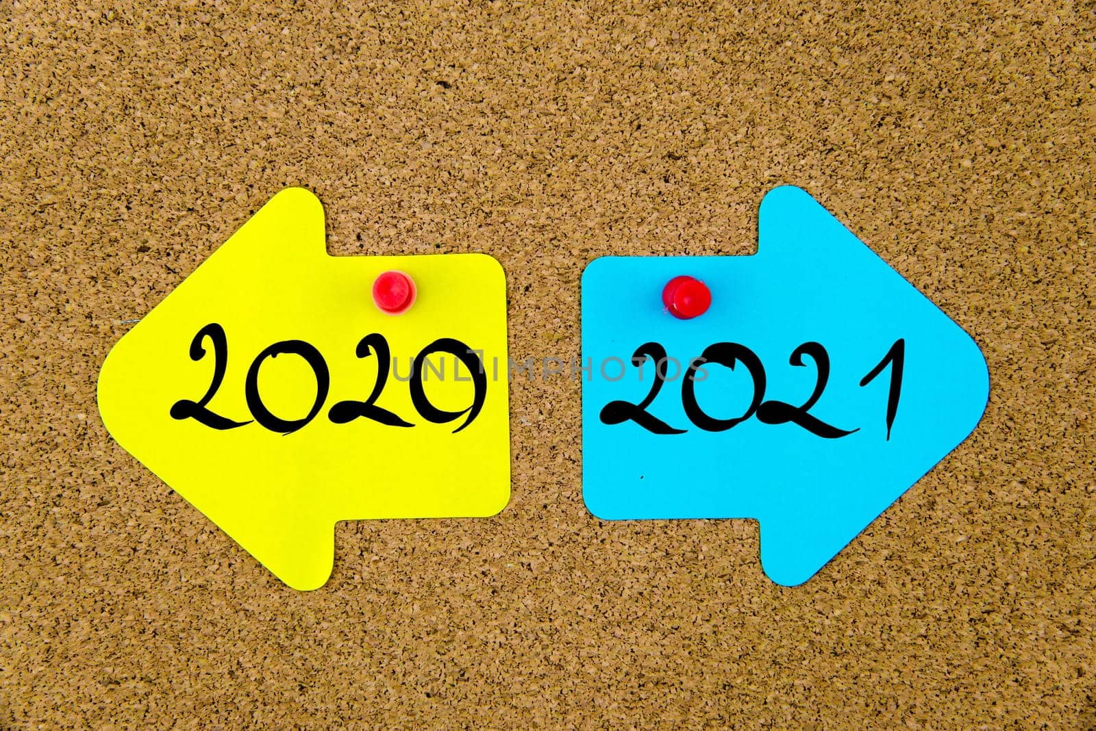 Blank yellow and blue paper notes in shape of opposite arrows pinned on cork board with thumbtacks, copy space available