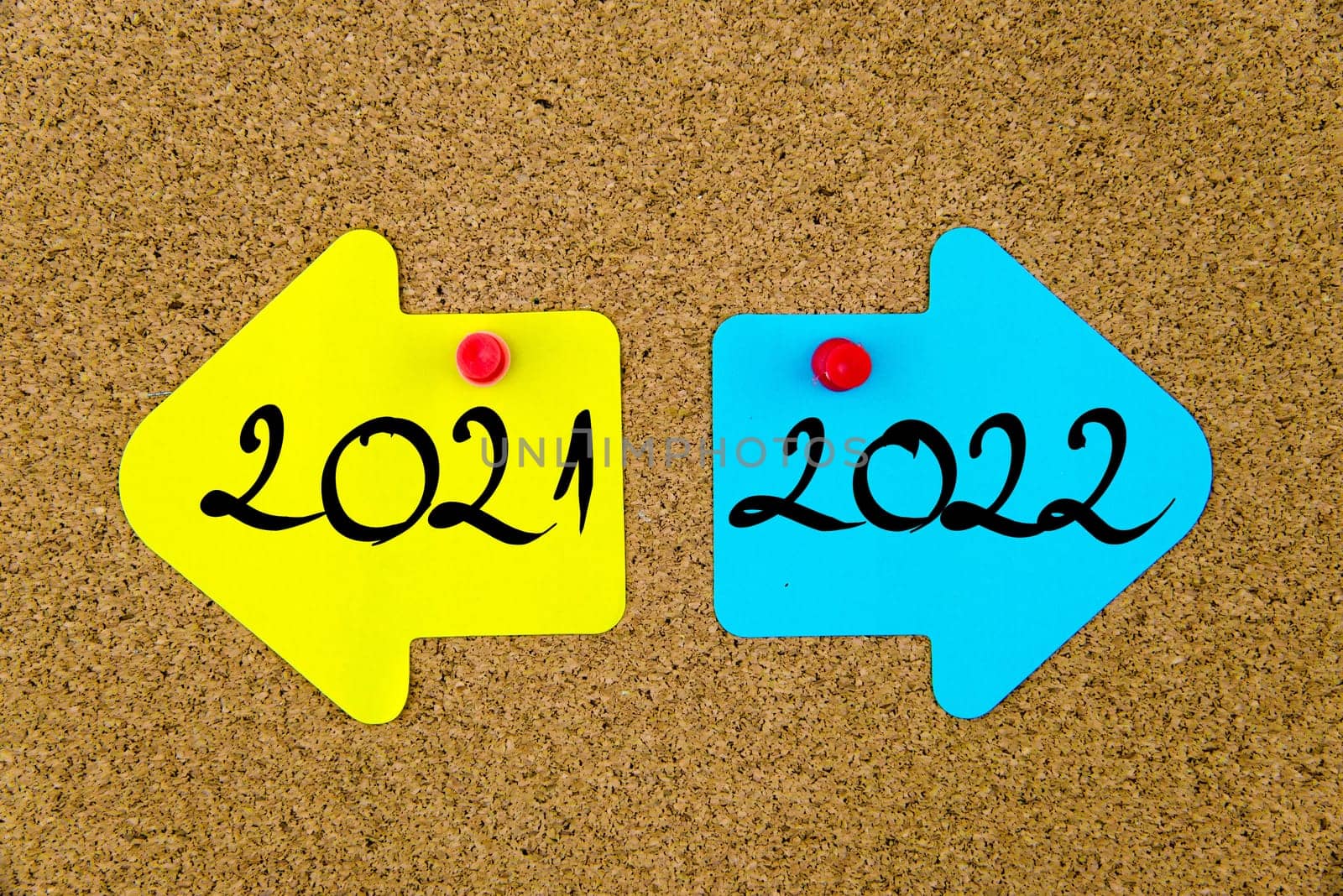 Blank yellow and blue paper notes in shape of opposite arrows pinned on cork board with thumbtacks, copy space available
