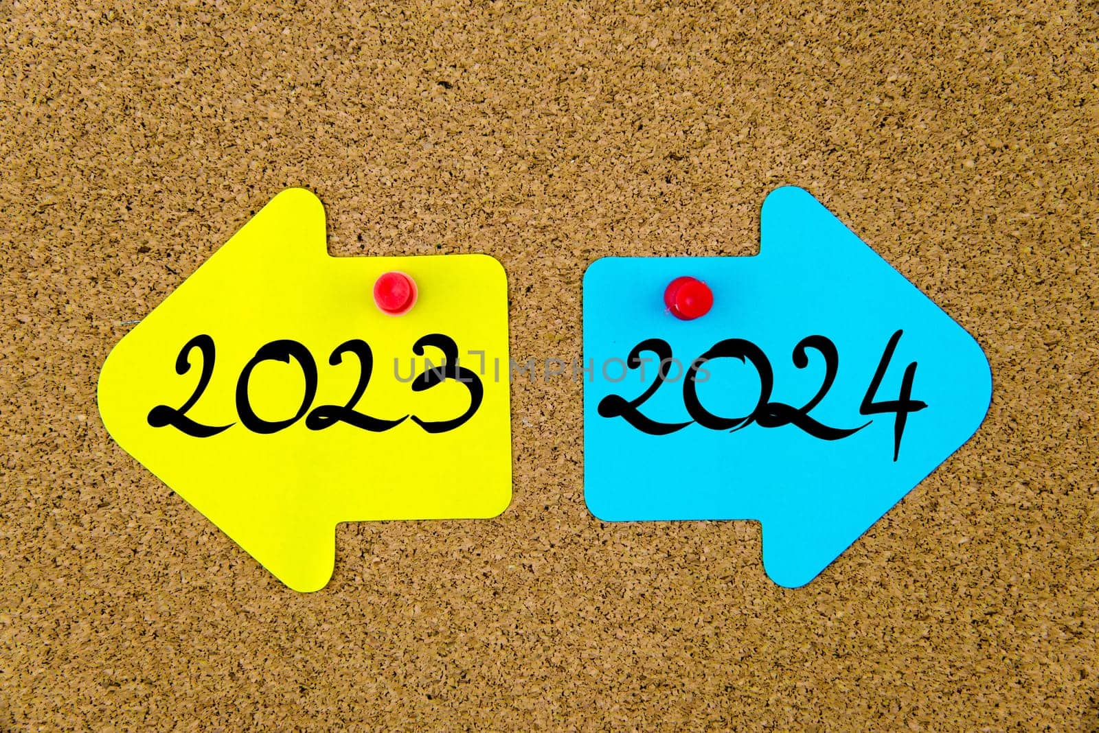 Blank yellow and blue paper notes in shape of opposite arrows pinned on cork board with thumbtacks, copy space available