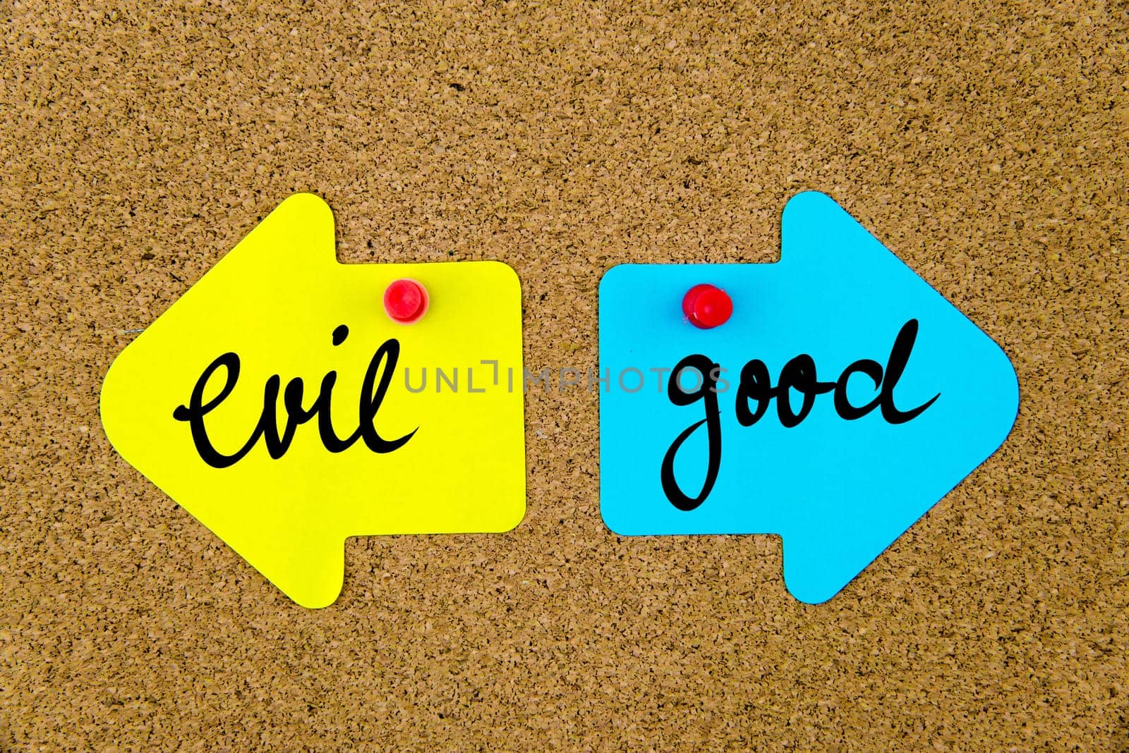 Blank yellow and blue paper notes in shape of opposite arrows pinned on cork board with thumbtacks, copy space available