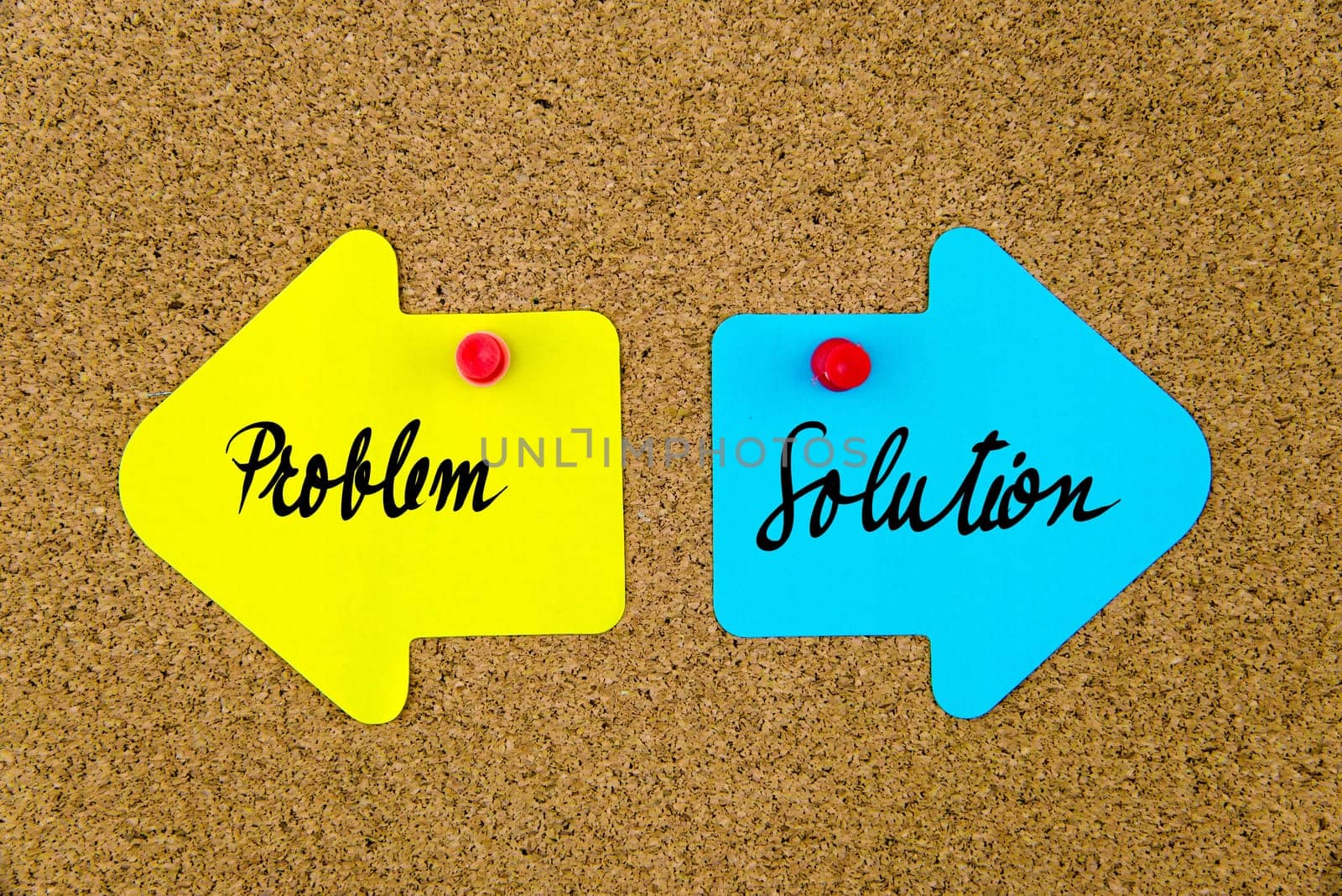 Blank yellow and blue paper notes in shape of opposite arrows pinned on cork board with thumbtacks, copy space available