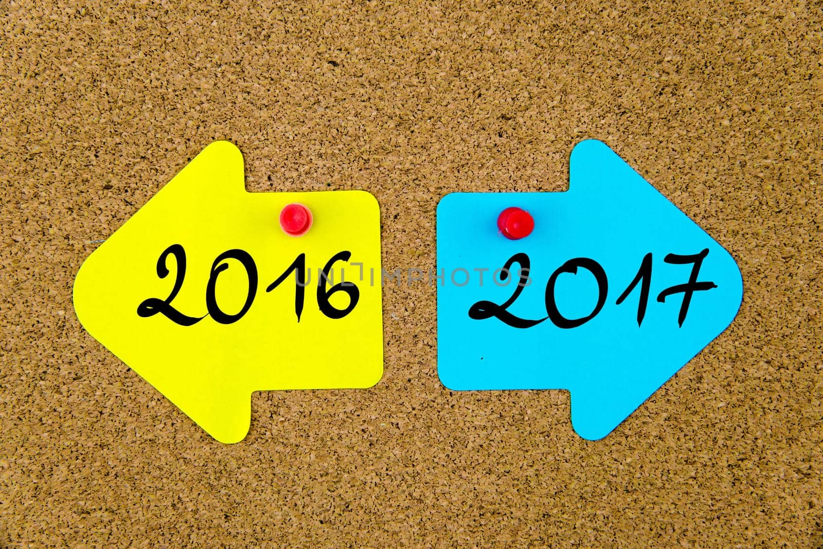 Blank yellow and blue paper notes in shape of opposite arrows pinned on cork board with thumbtacks, copy space available