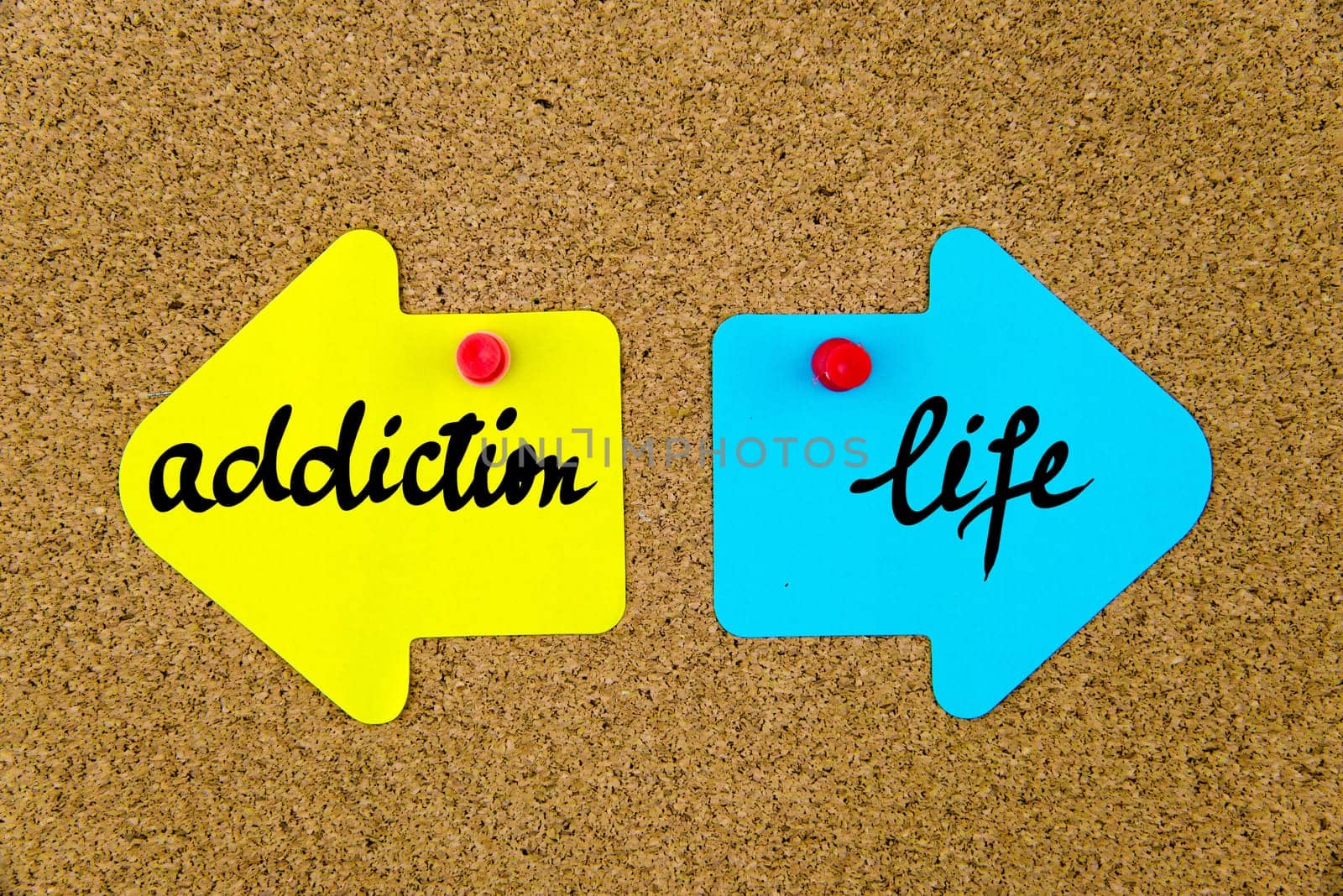 Blank yellow and blue paper notes in shape of opposite arrows pinned on cork board with thumbtacks, copy space available