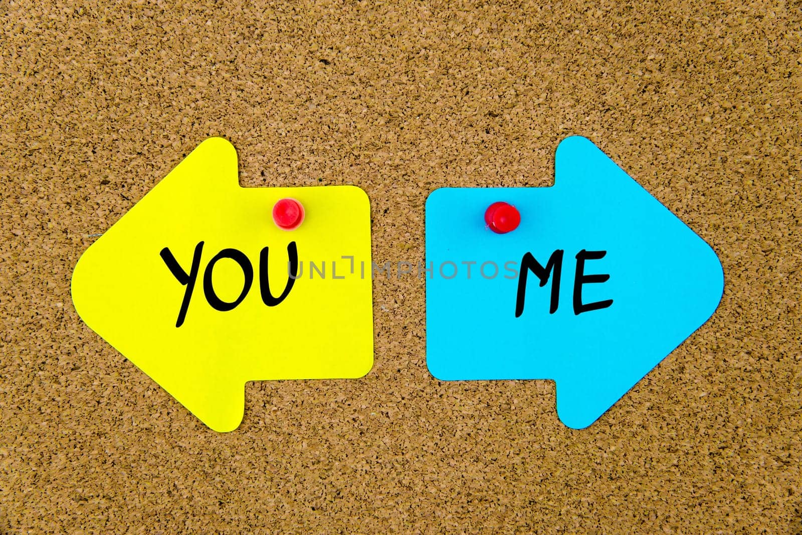 Blank yellow and blue paper notes in shape of opposite arrows pinned on cork board with thumbtacks, copy space available