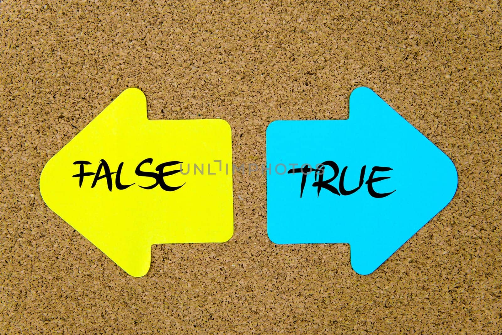 Message False versus True on yellow and blue paper notes as opposite arrows pinned on cork board with thumbtacks. Choice conceptual image