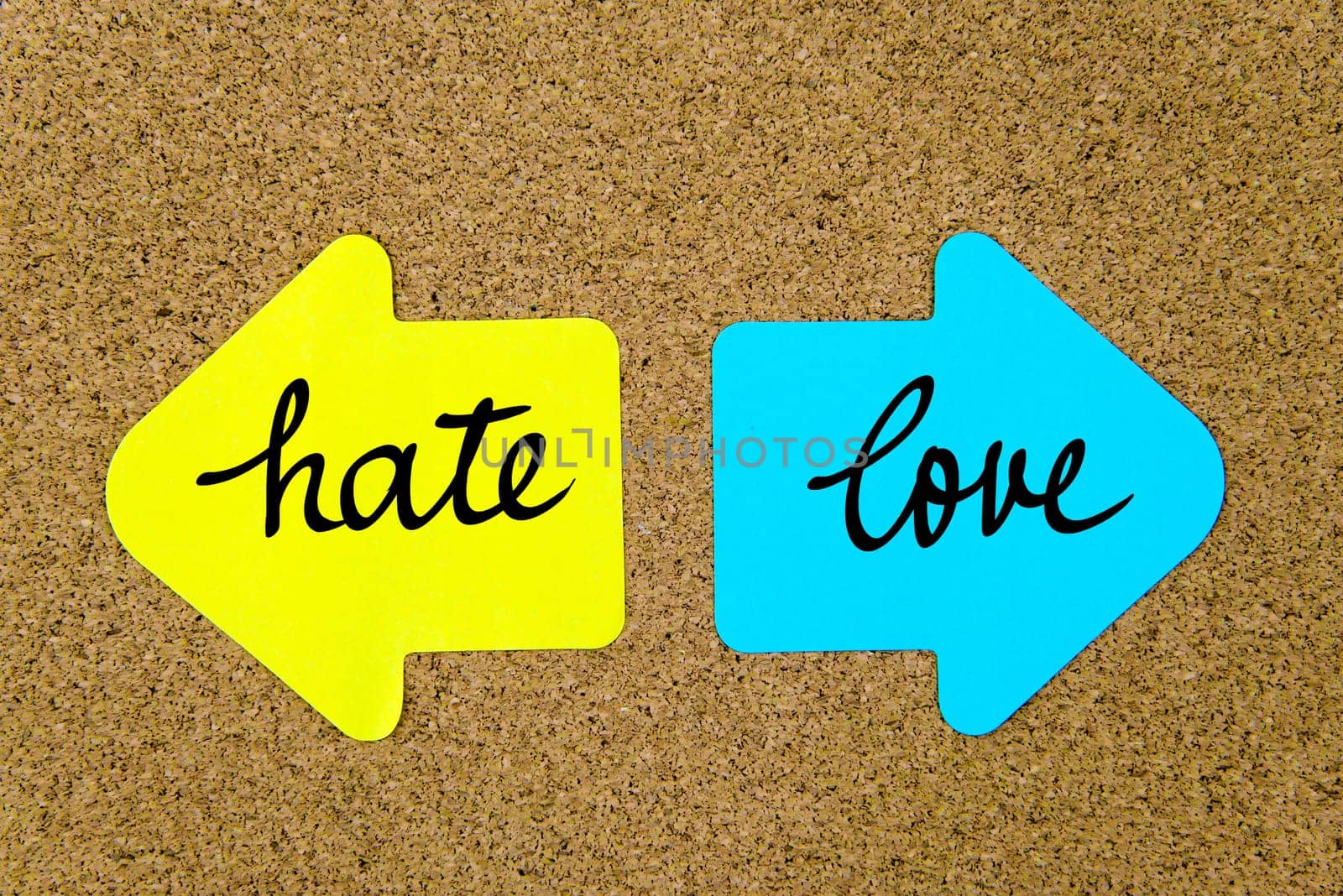 Message Hate versus Love on yellow and blue paper notes as opposite arrows pinned on cork board with thumbtacks. Choice conceptual image