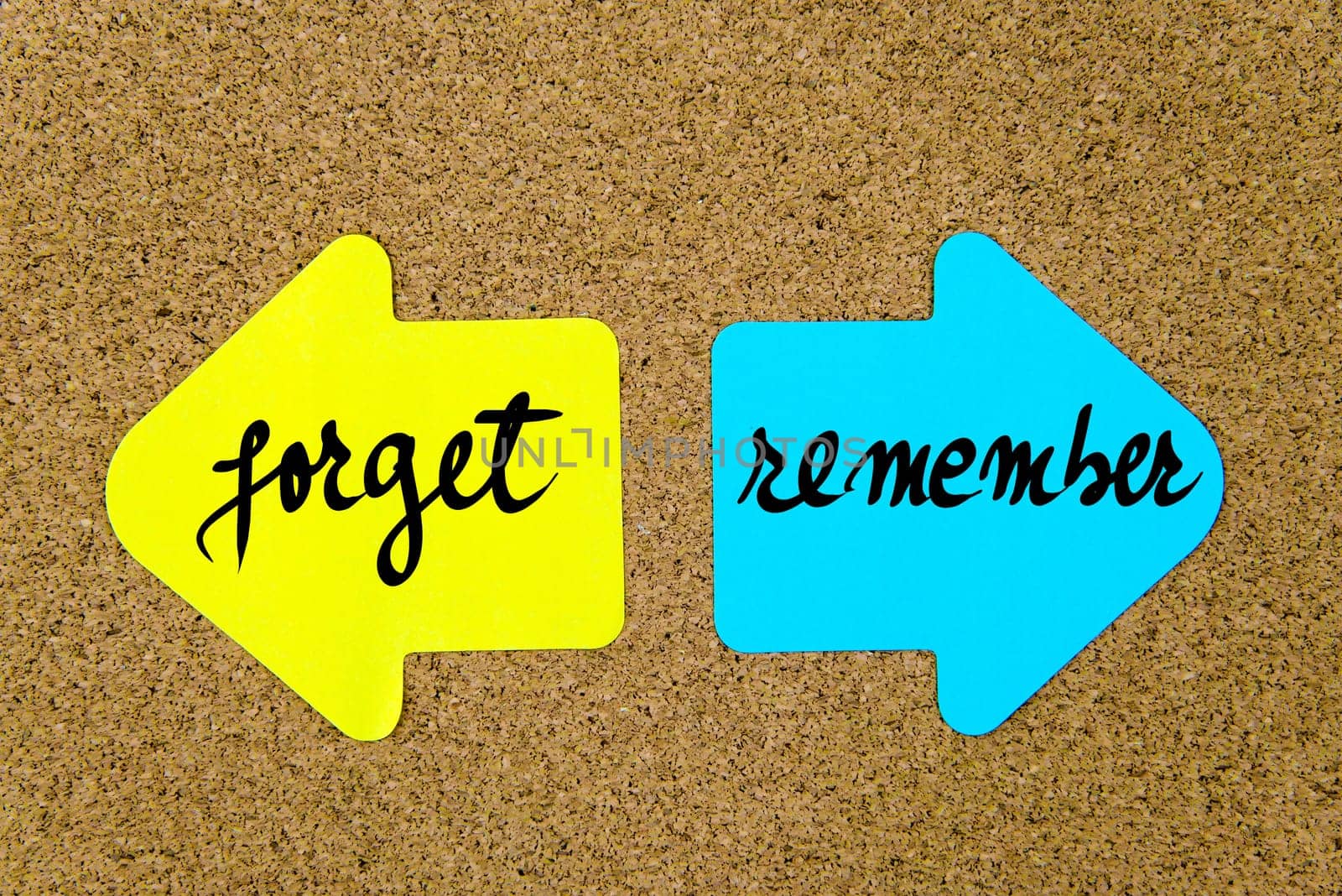 Message Forget versus Remember on yellow and blue paper notes as opposite arrows pinned on cork board with thumbtacks. Choice conceptual image